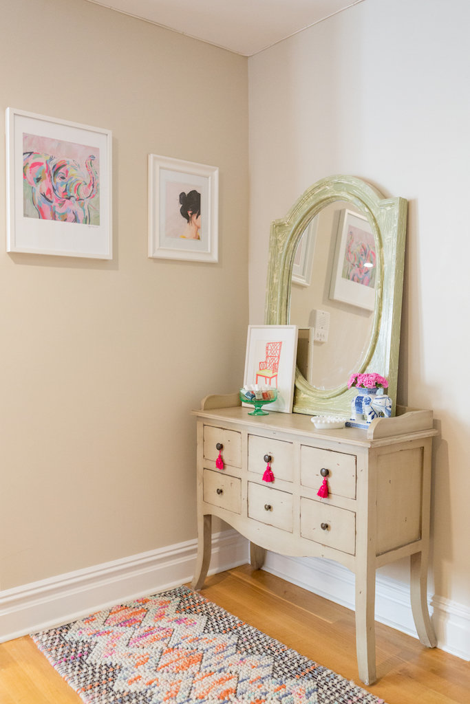 A vintage vanity and mirror with framed art.