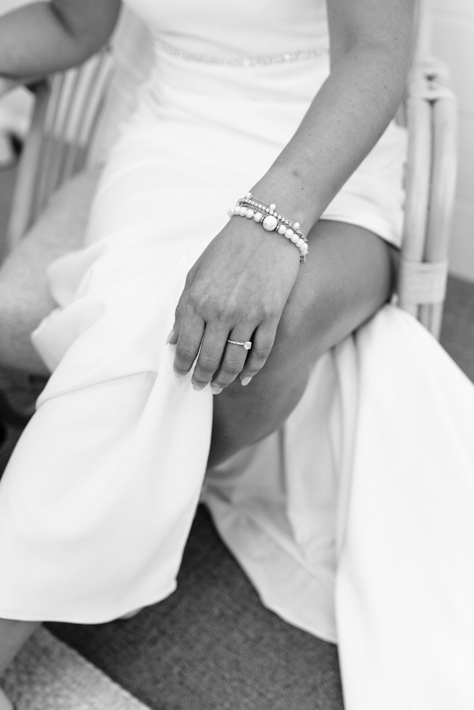 Detail of bride wearing pearl bracelets and wedding dress.