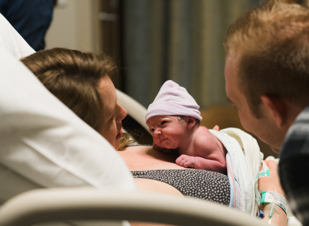 A brand new baby lifts its head to gaze at her mother. Birth story by Diane Owen Photography.