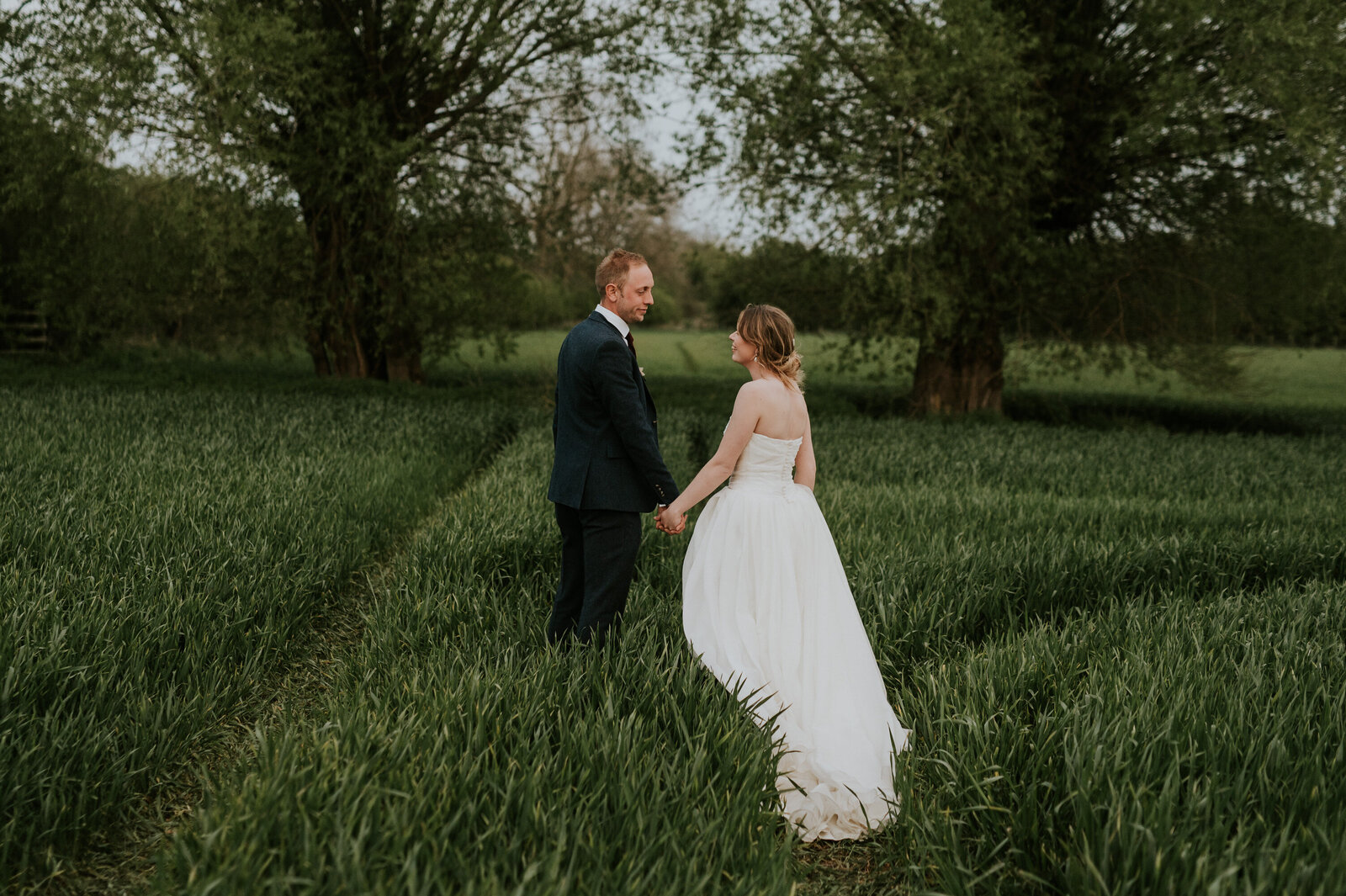 Bride and grromholding hands in a wheat field