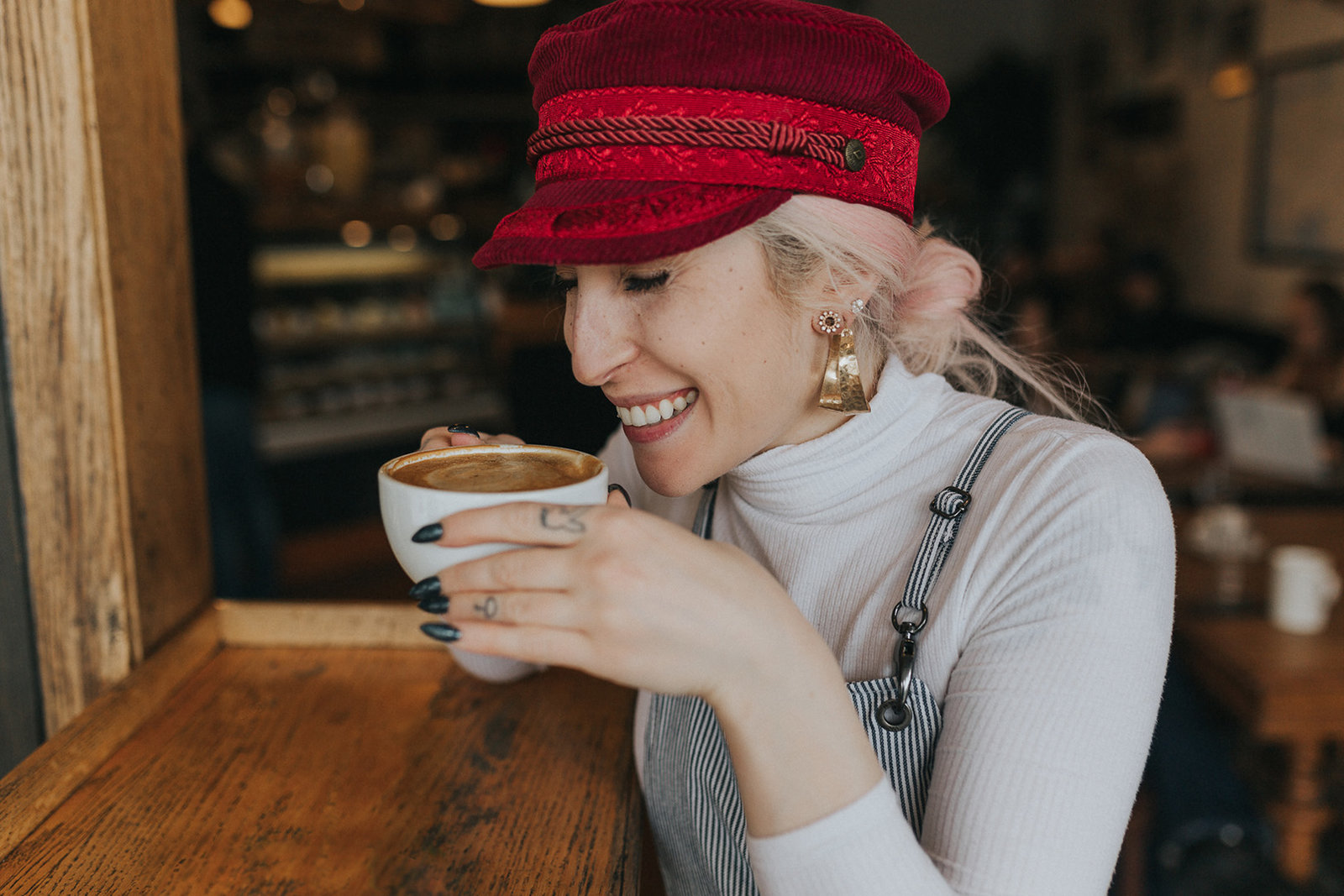 fashion blogger smiling, enjoying a cup of coffee