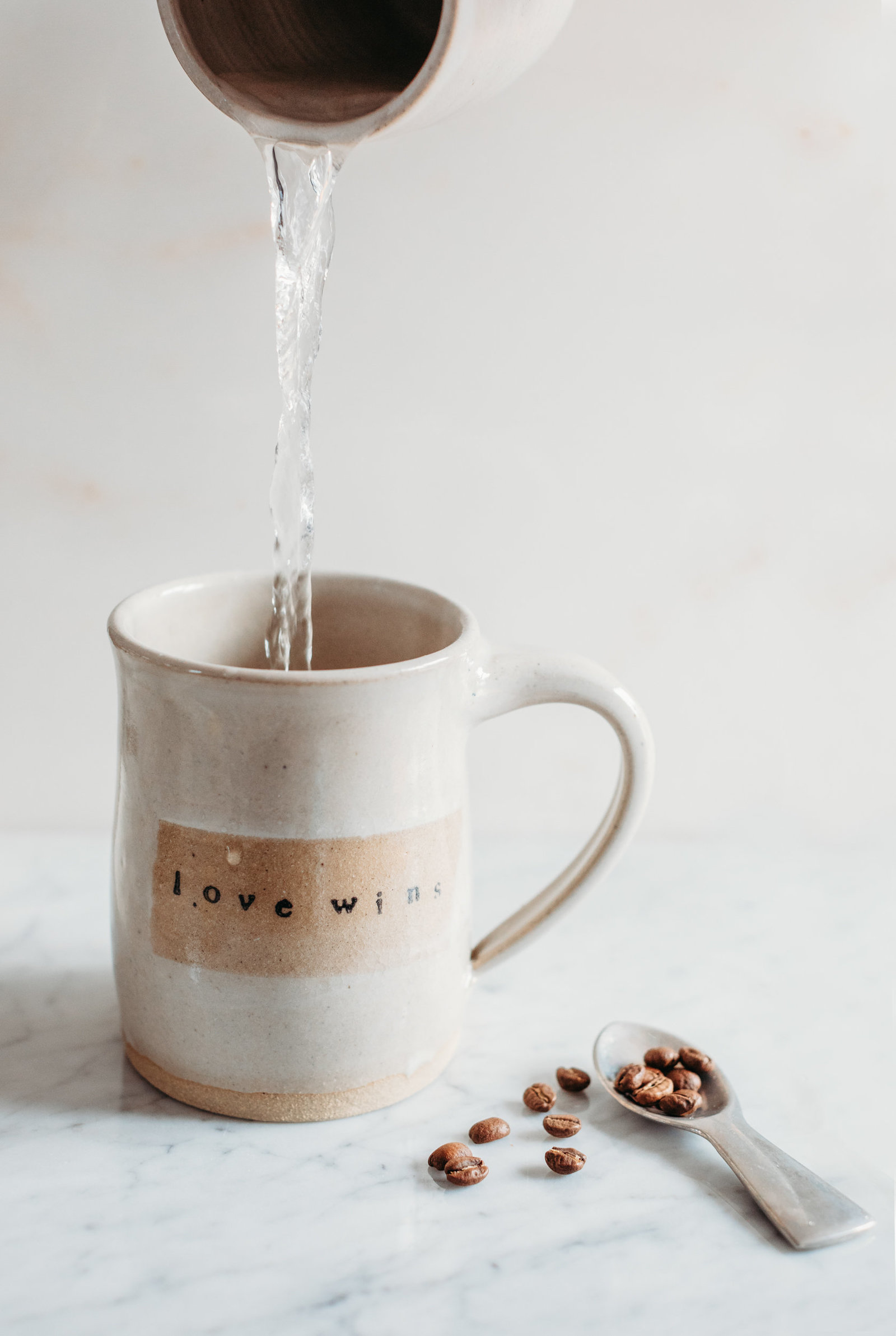 product shot of a tan coffee mug and coffee beans