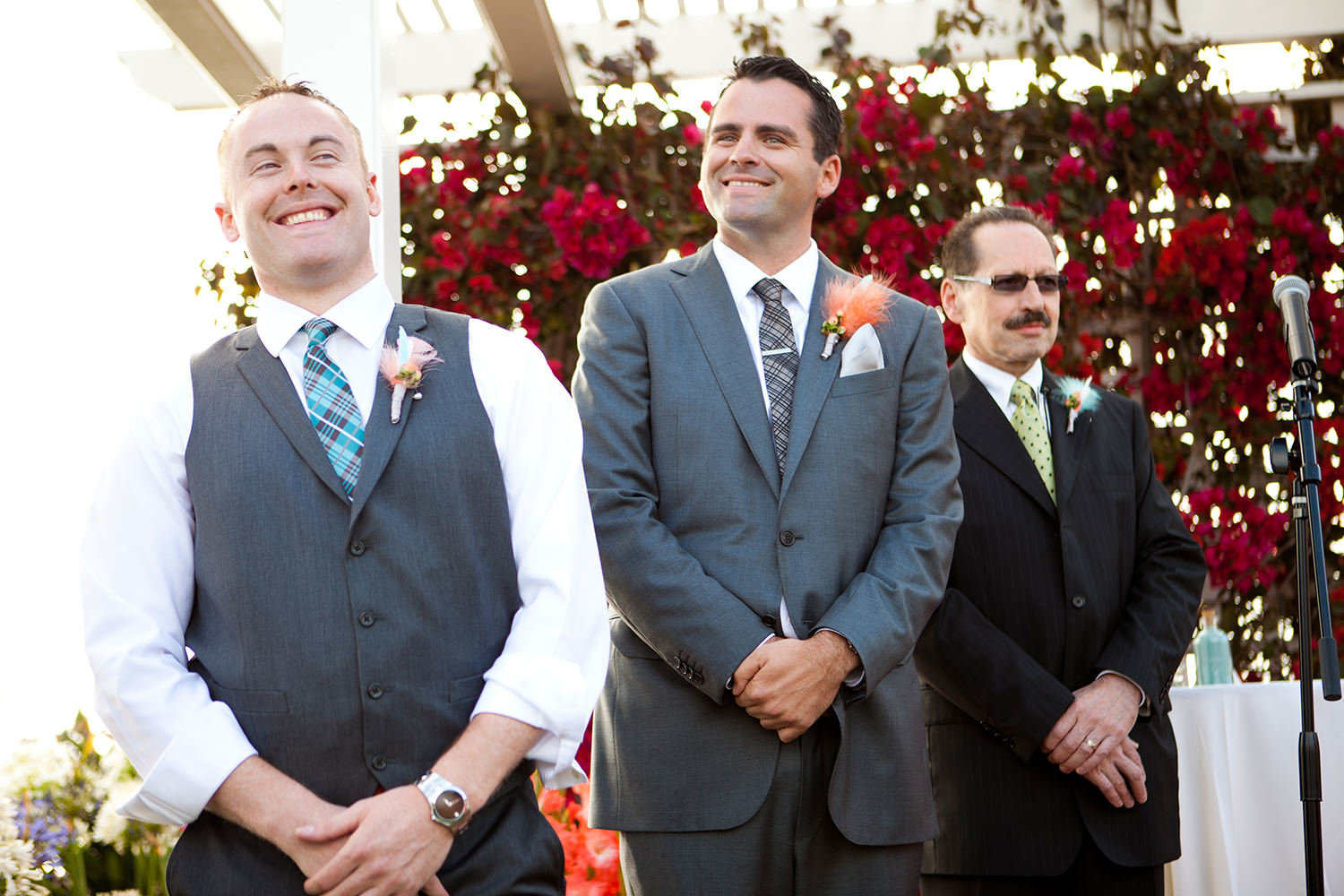 groom smiling while bride walks down the aisle