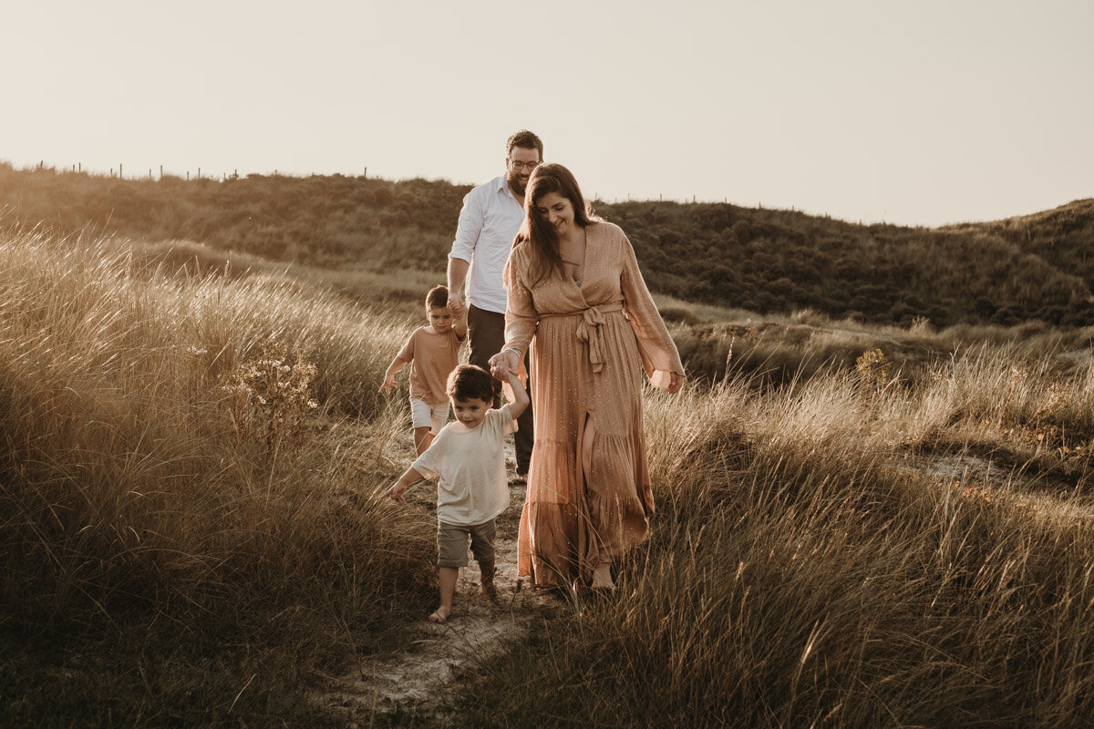 gezin loopt door de duinen tijdens zonsondergang