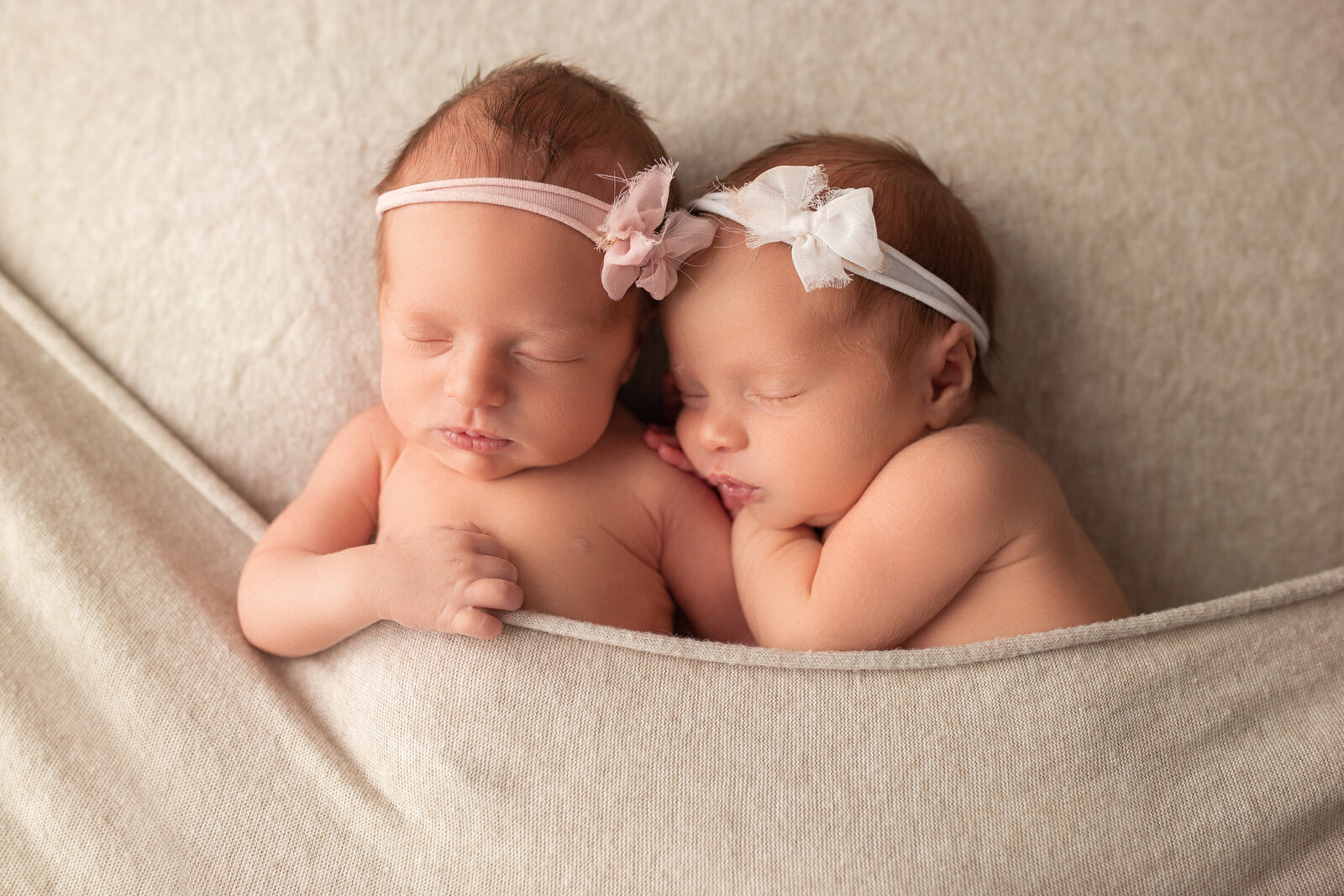Newborn twin siblings cuddling