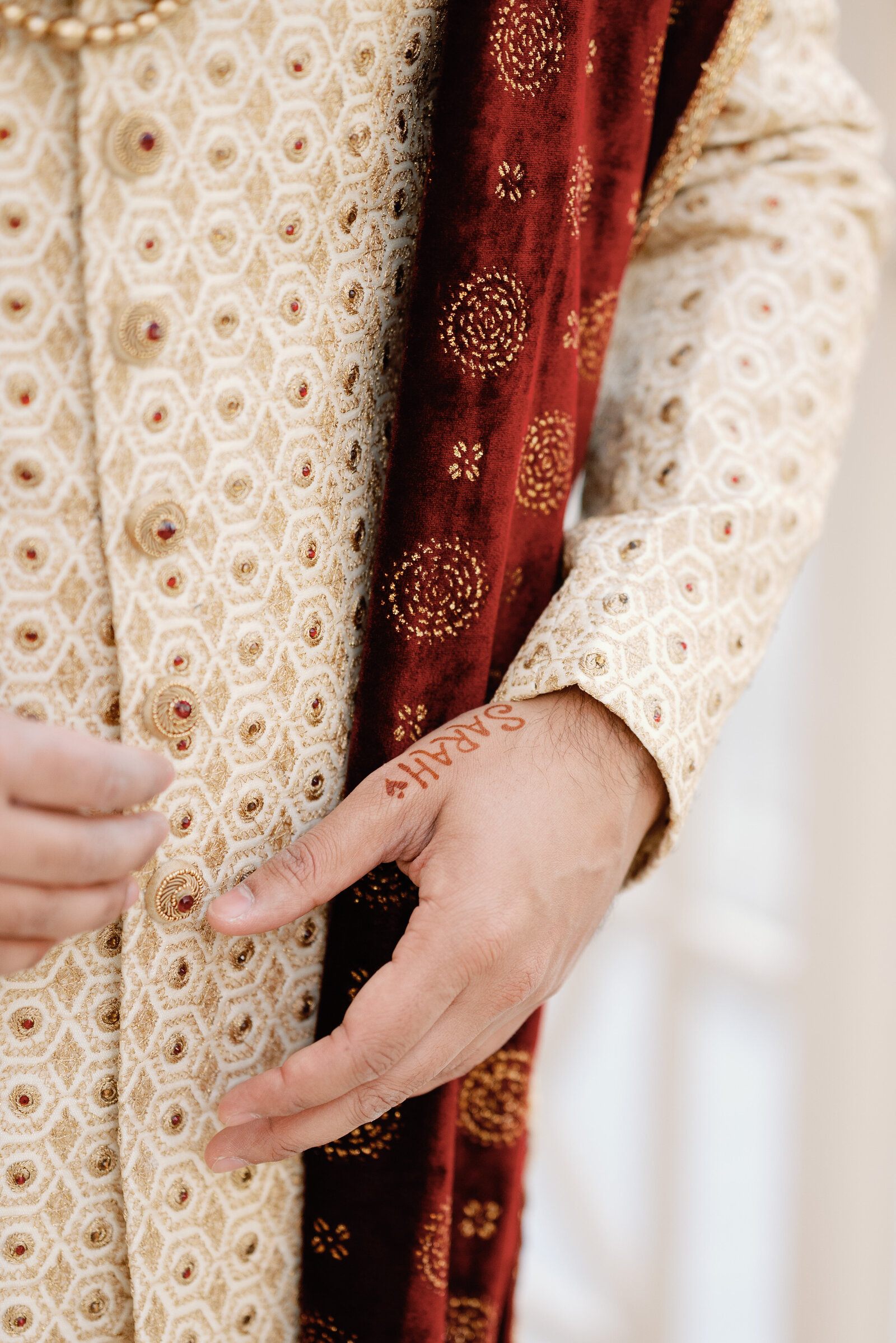 detail of grooms hand with his brides name in henna on the base of his thumb