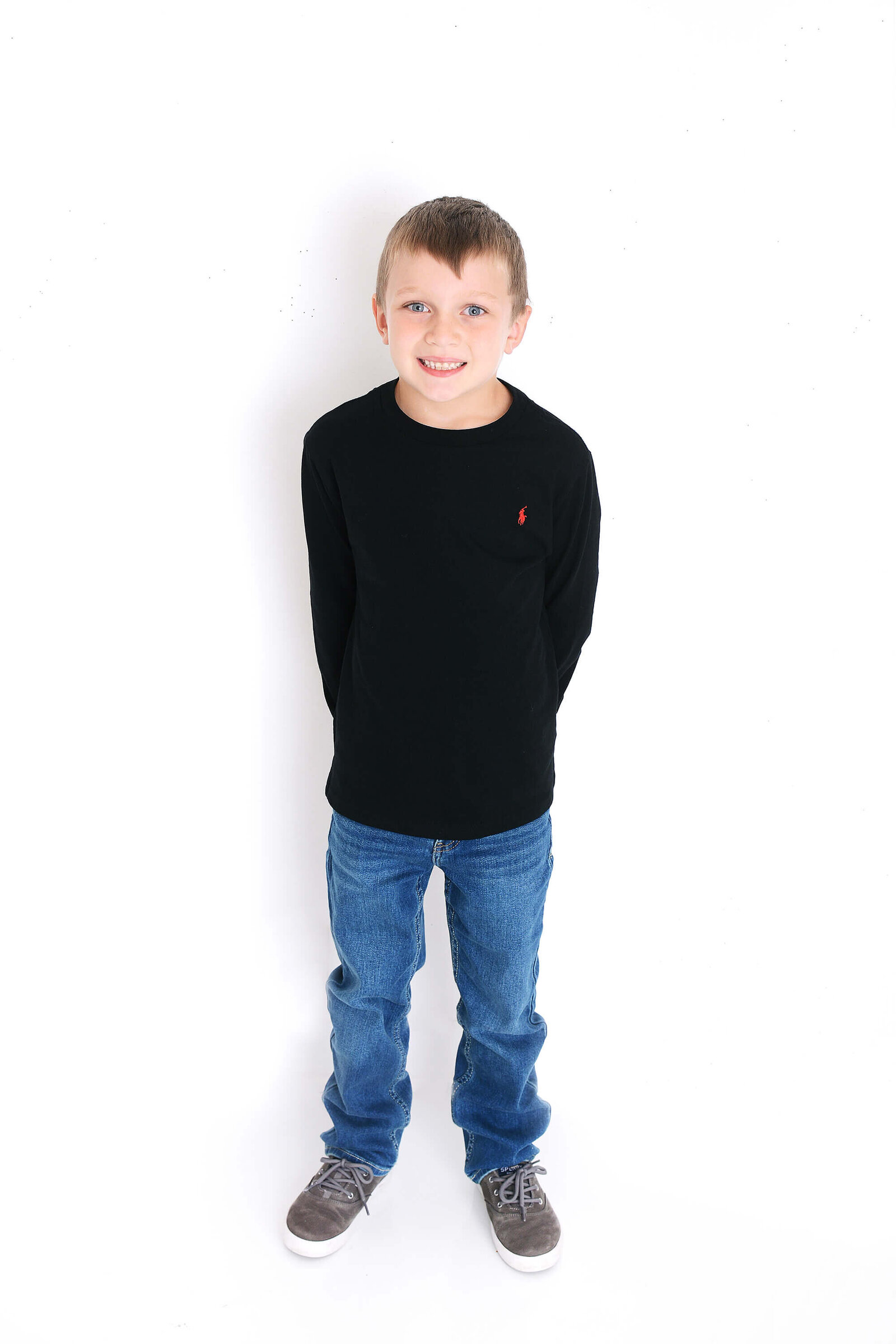 boy smiles at the camera in front of a white background