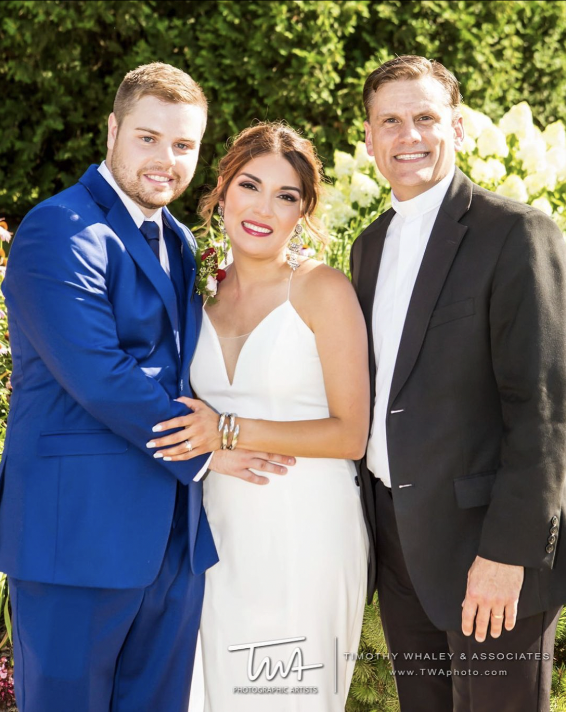 Bride and groom smile for portrait with wedding officiant