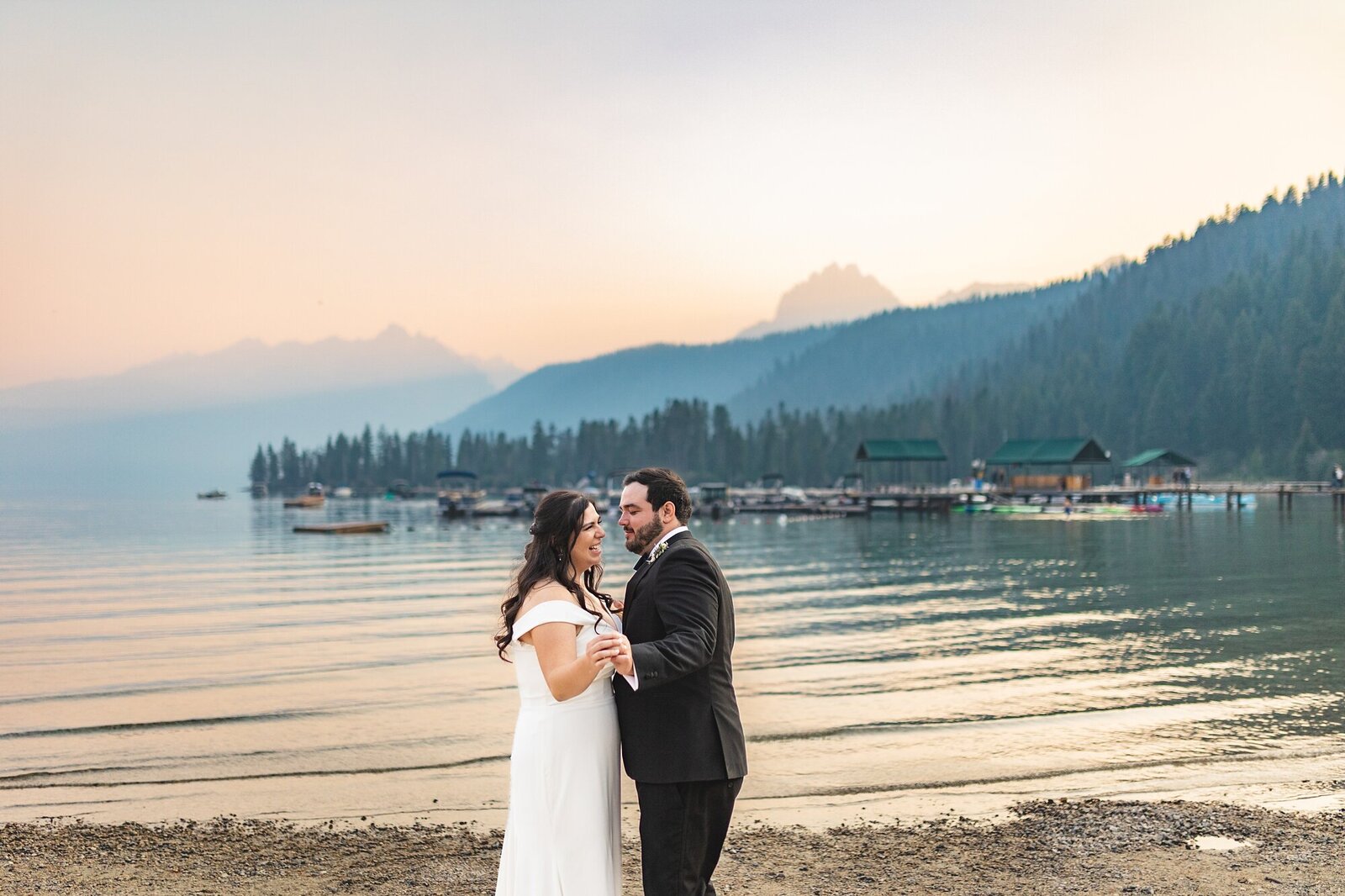 bride and groom dancing in front of sawtooth mountains and lake