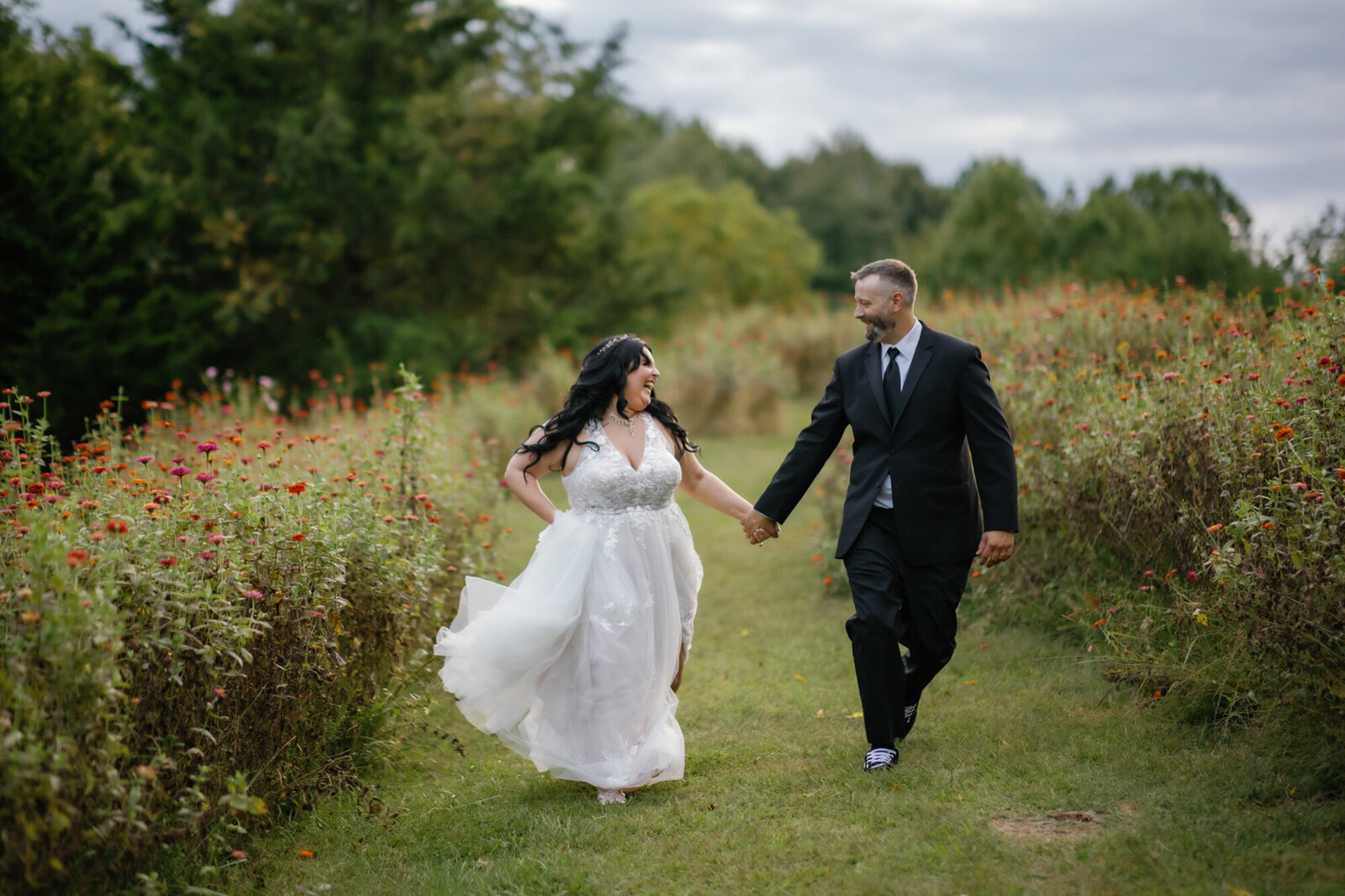 gatlinburg photographers photographs bride and groom holding hands and running through a flower field as they elope to Gatlinburg 