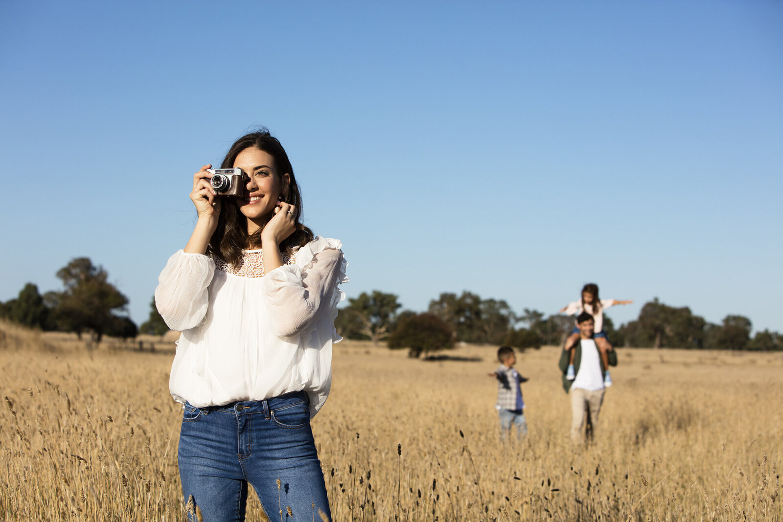 Photography in field taking a photo with her family in the background