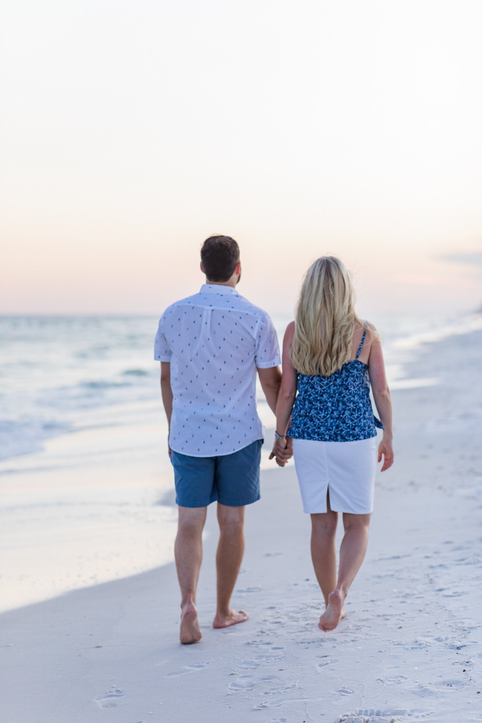 Couple walking down Pensacola Beach at sunset