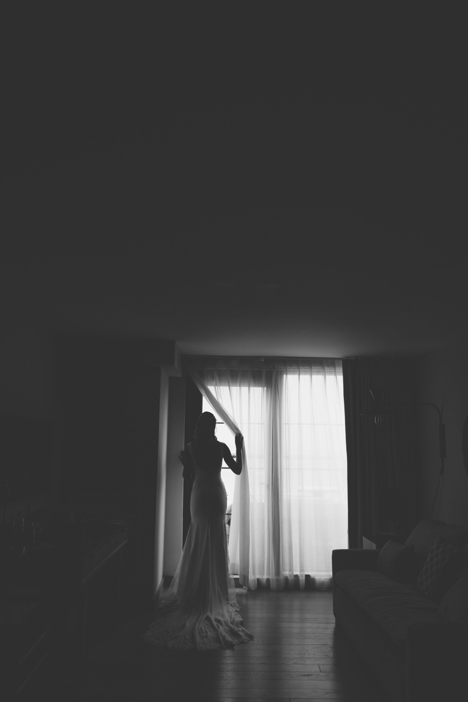 black and white photo of bride looking out the window at  Gurneys Montauk Resort wedding