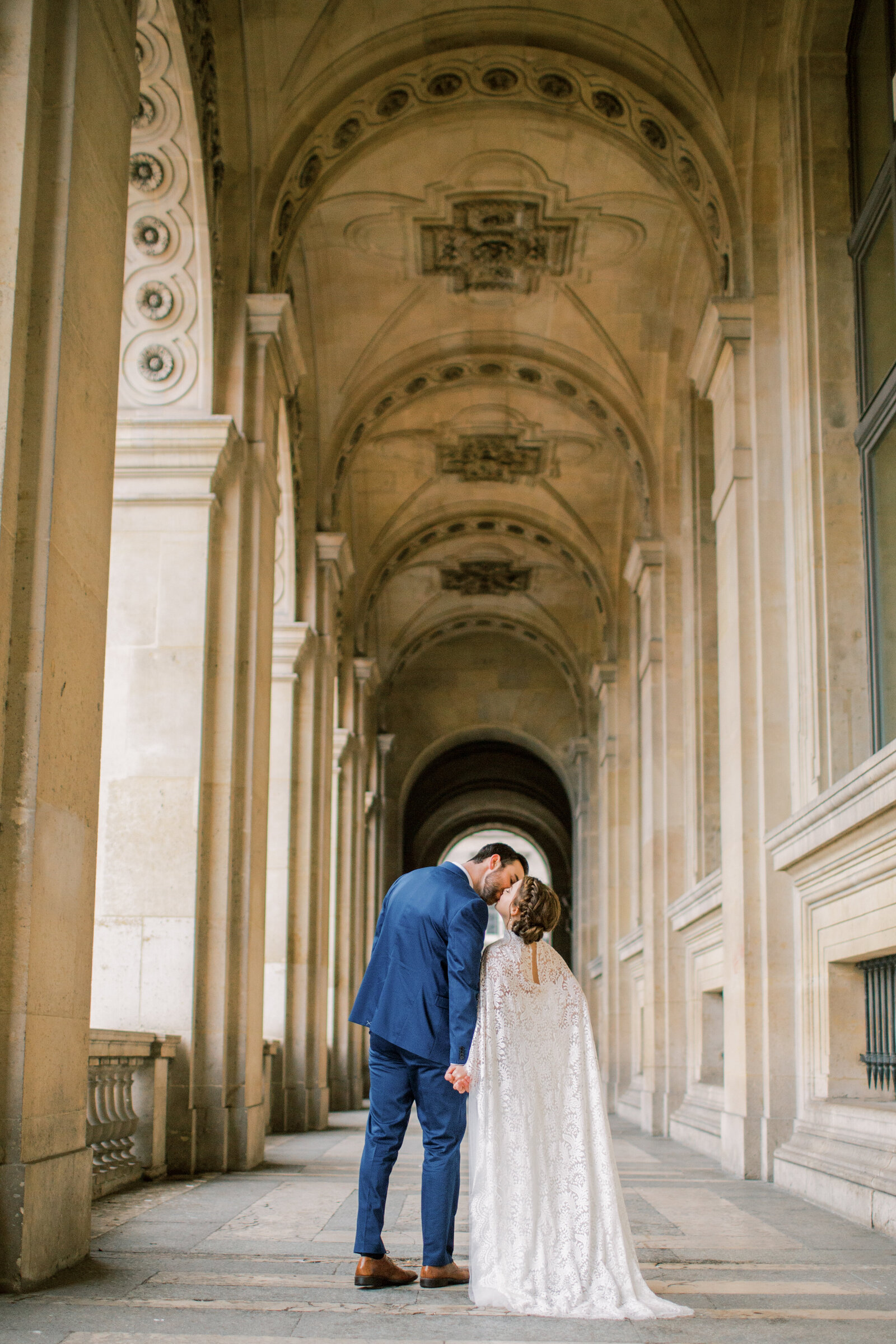 bride and groom kissing under arches in paris france