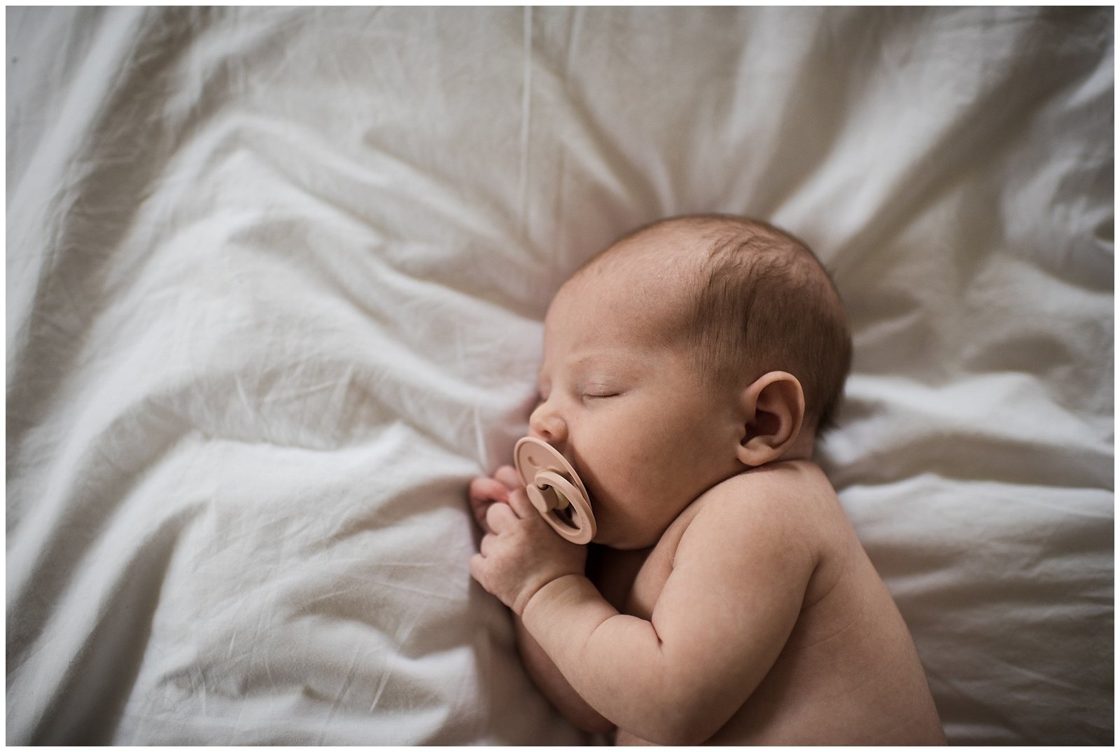 Newborn baby laying on her side on white sheet lifestyle newborn photoshoot Emily Ann Photography Seattle Photographer