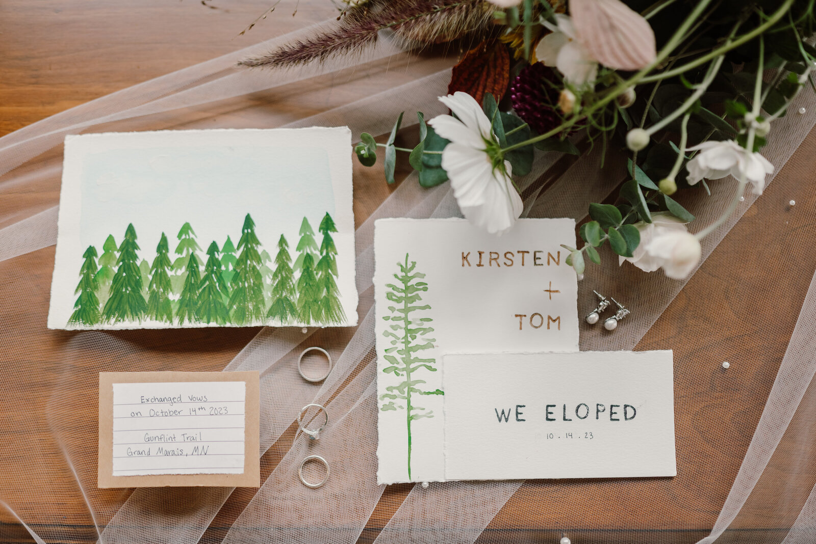 Forest elopement flat lay of invitational suite placed on bride's veil
