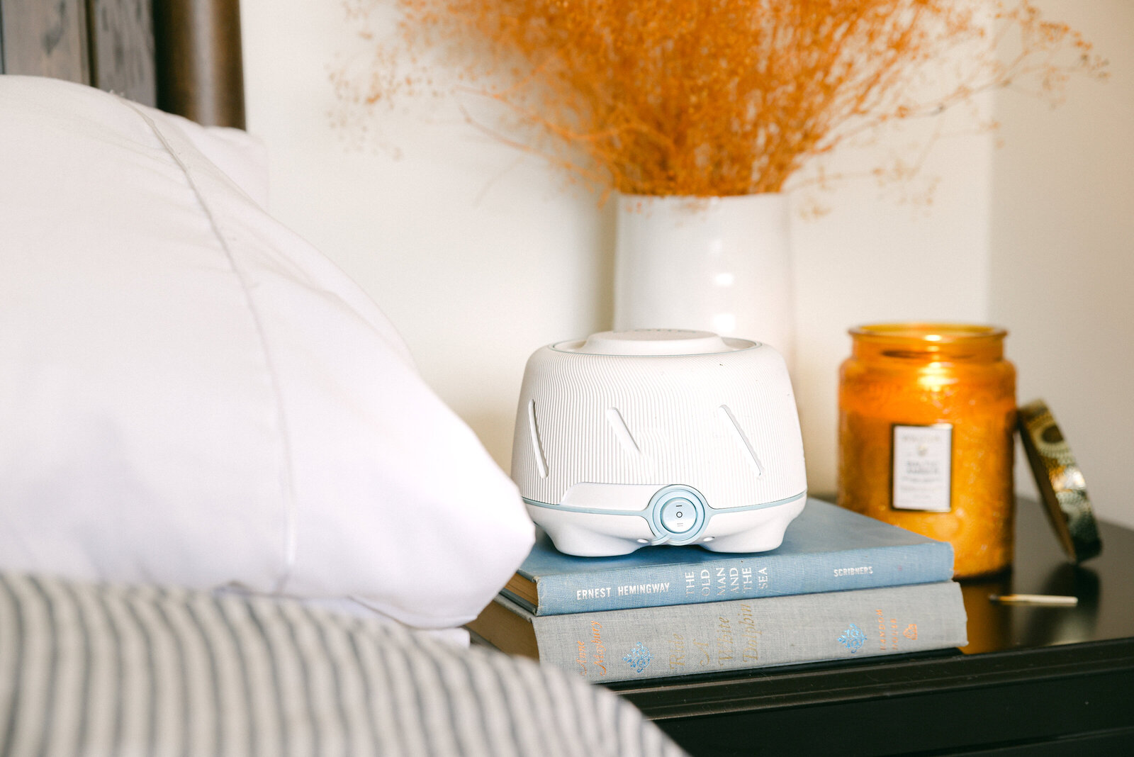 Yogasleep white noise machine styled next to bed with candle