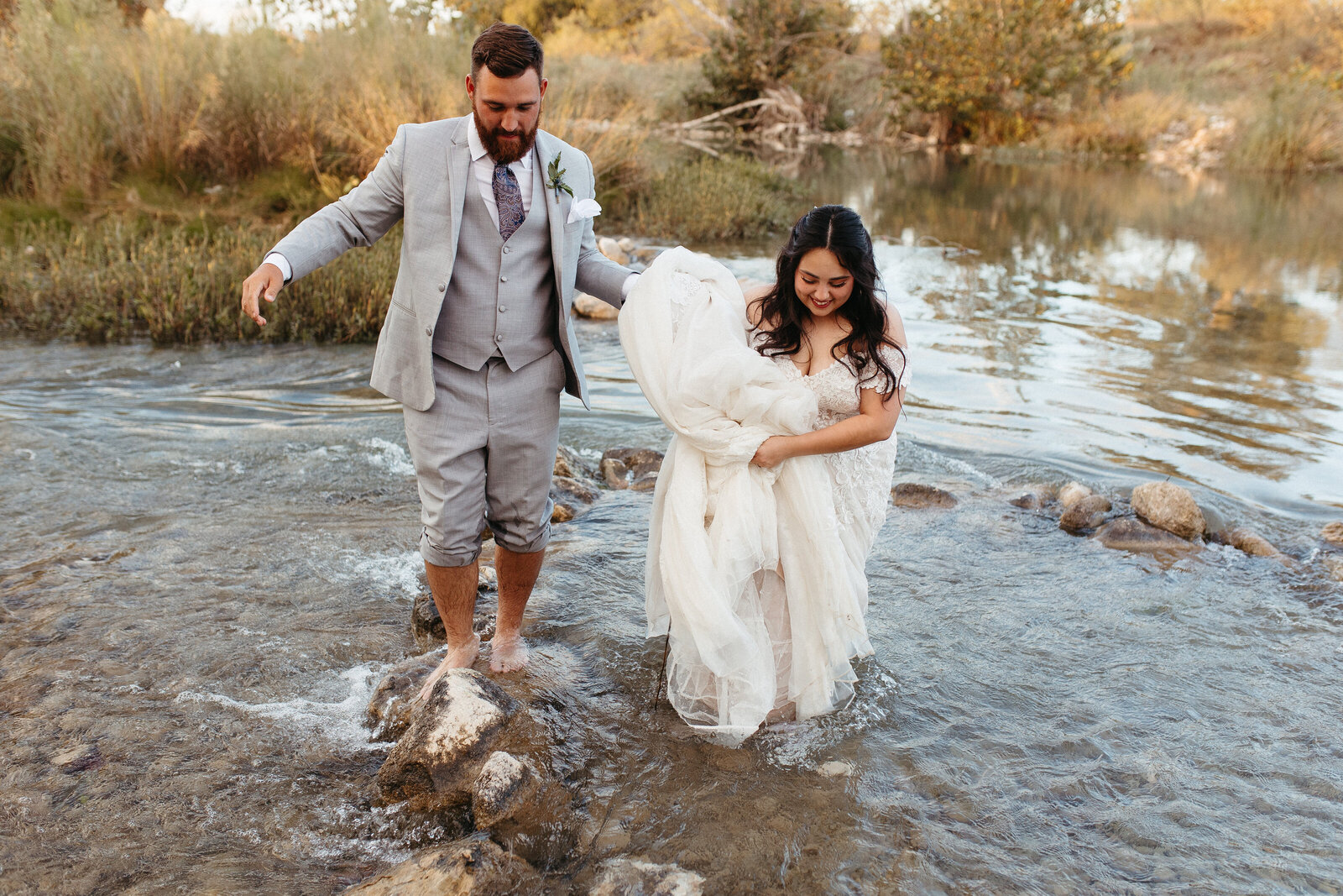 Bride and groom walking through river