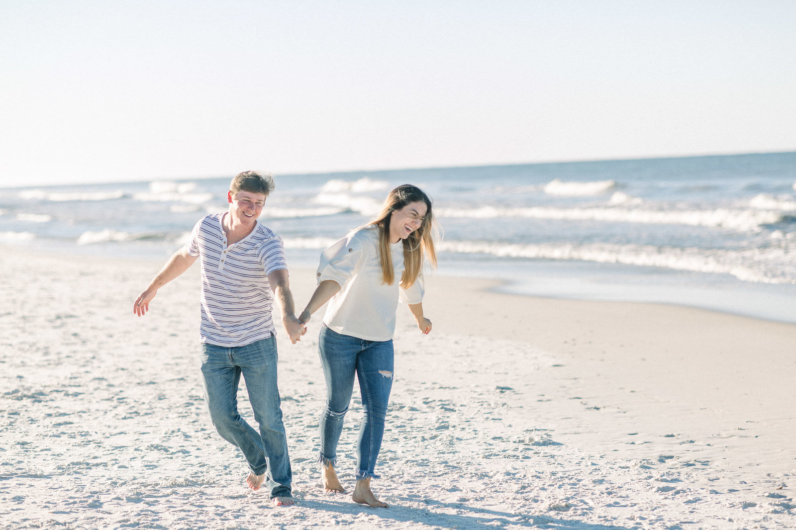 Laughing and running down the beach captured by Staci Addison Photography