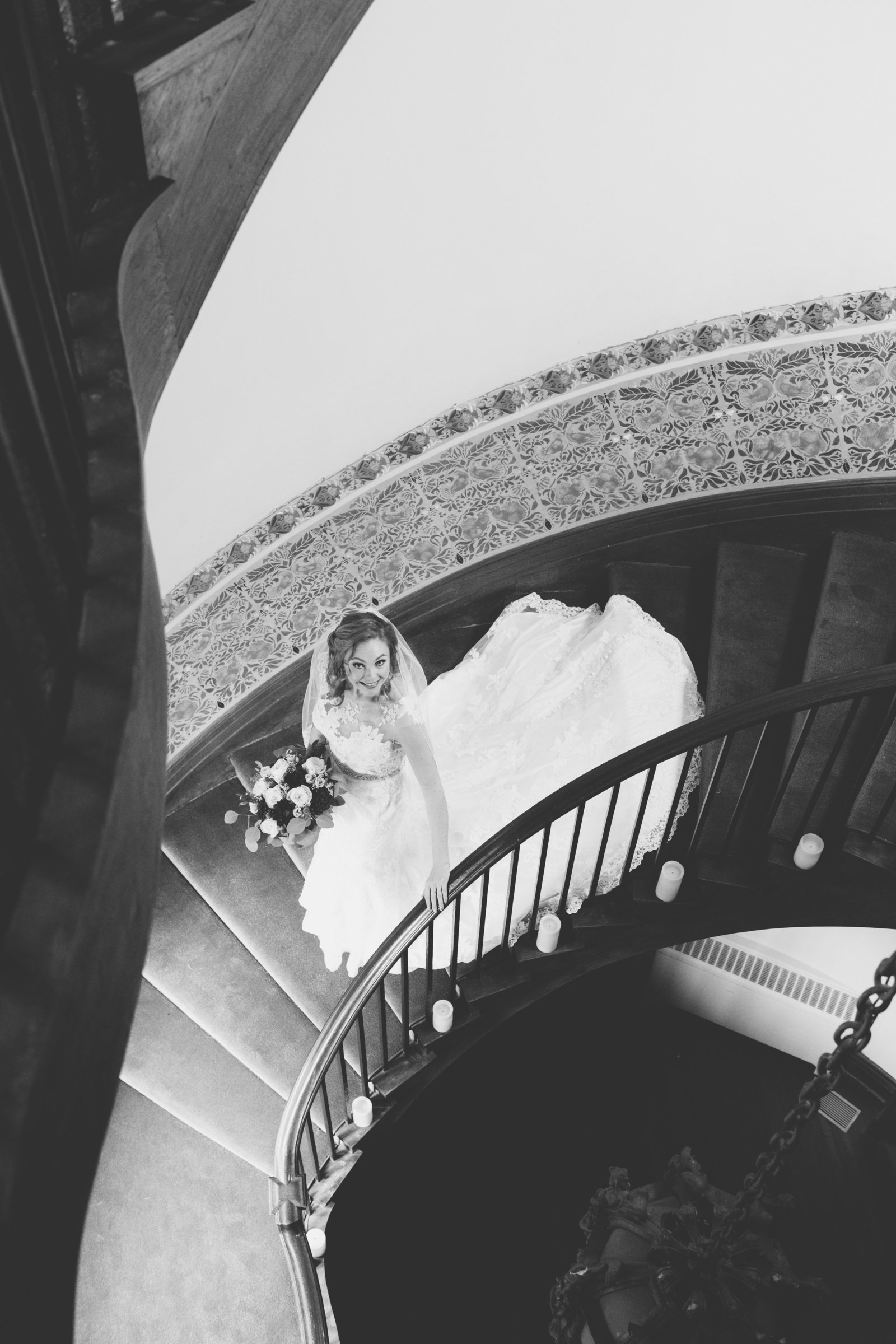 black and white photo of bride walking down the stairs at Coindre Hall