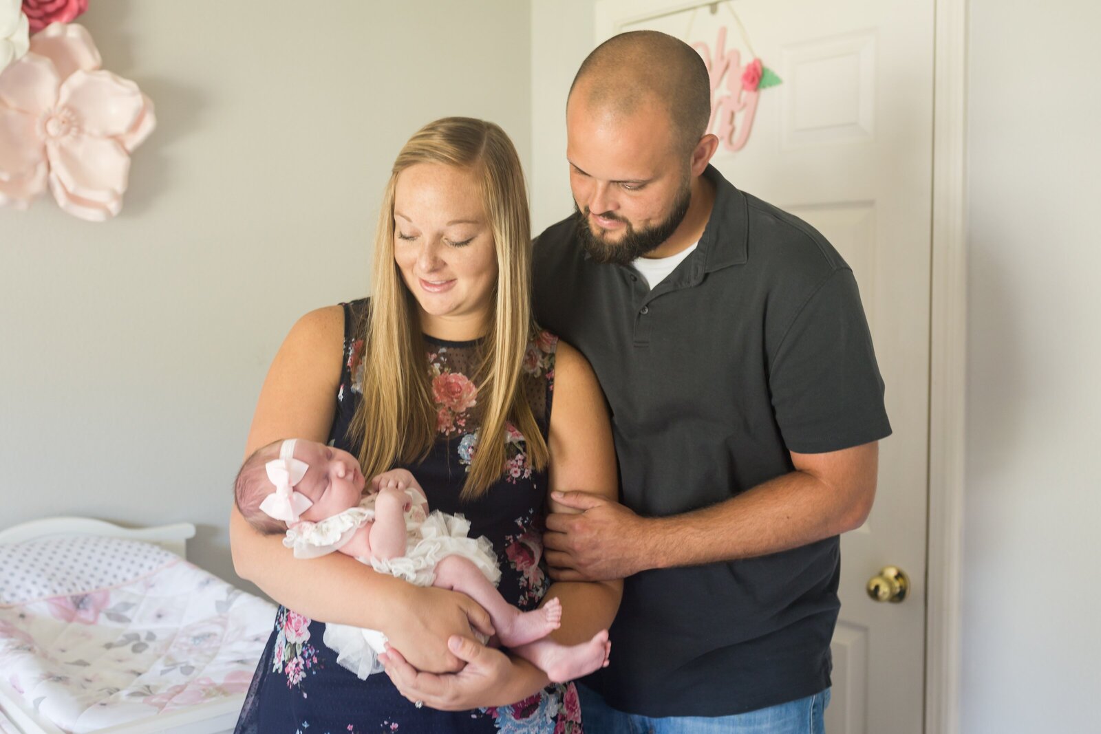 Mom and dad holding newborn daughter  during in-home photography session in Pensacola , FL