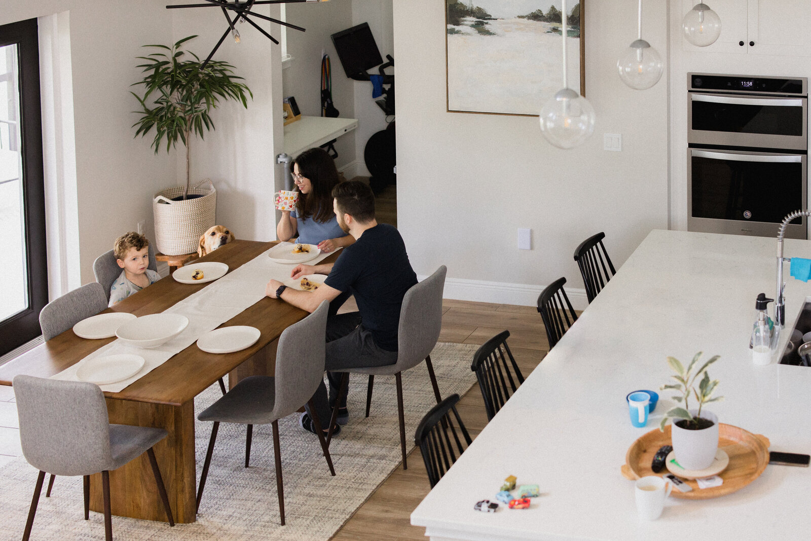 Family sits around their dining room table while their dog looks on
