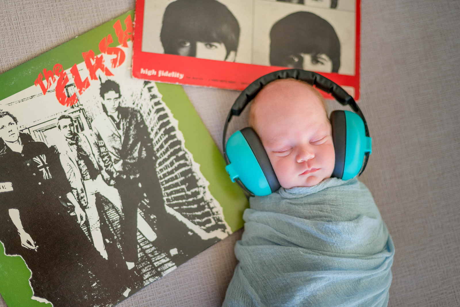 Newborn posed at home on furniture in lifestyle session Boston listening to music headphones on