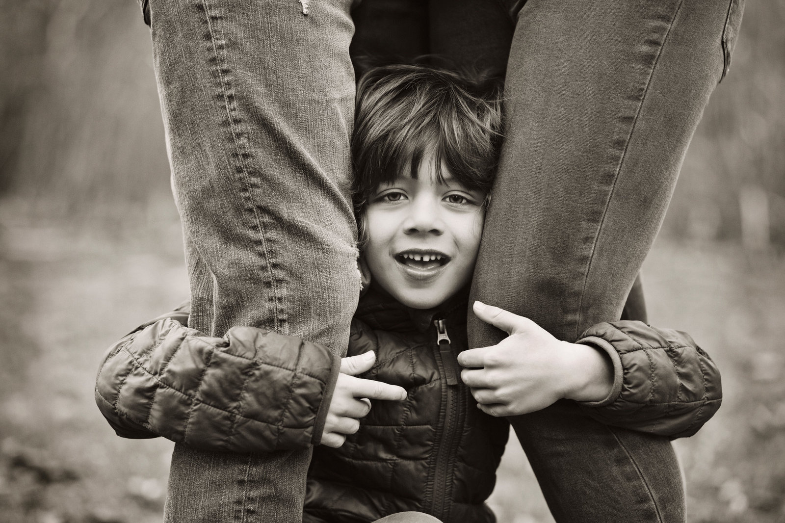Boy peeking from behind his parents legs