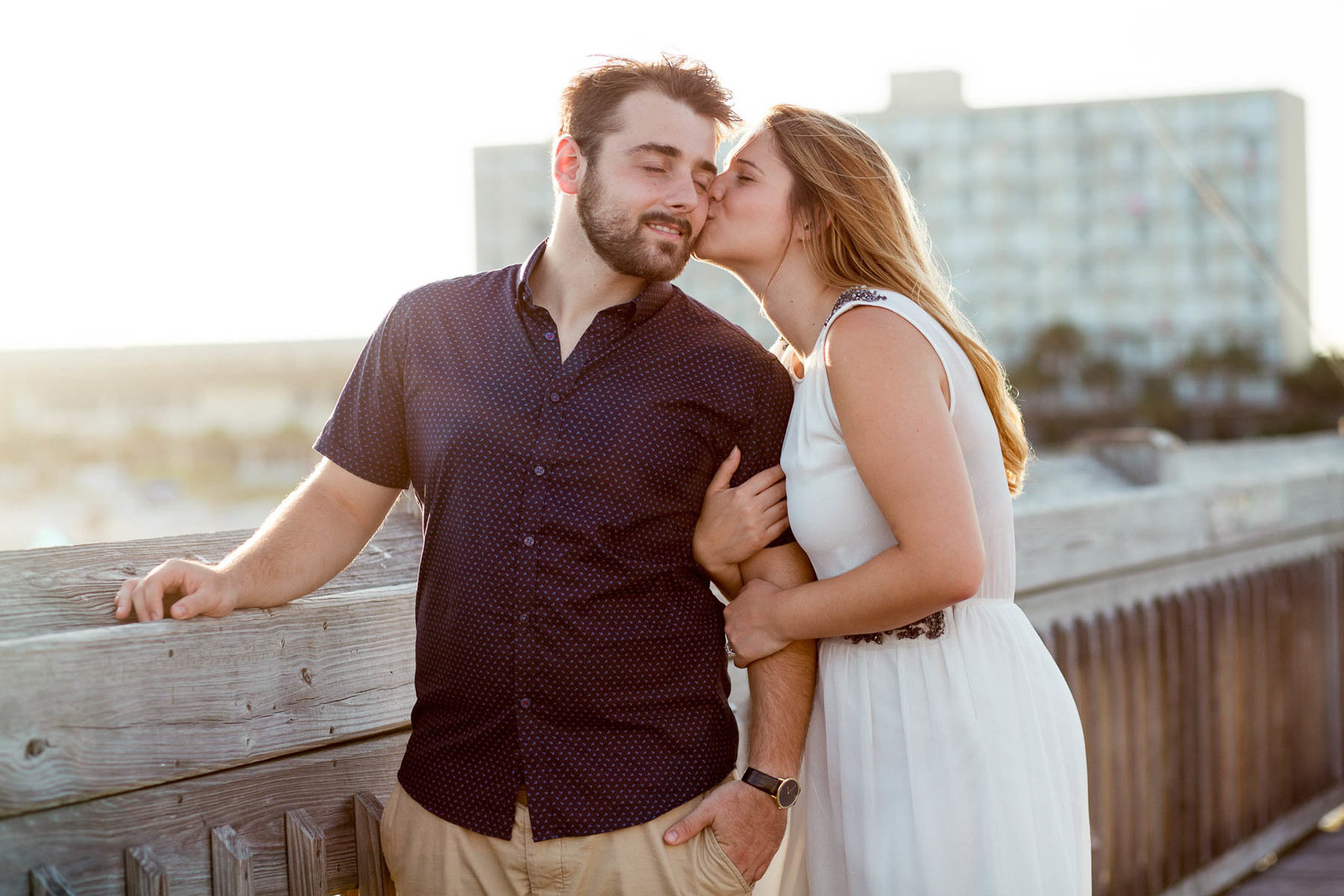 Engaged Couple kiss at sunset on pier, Folly beach in Charleston, South Carolina