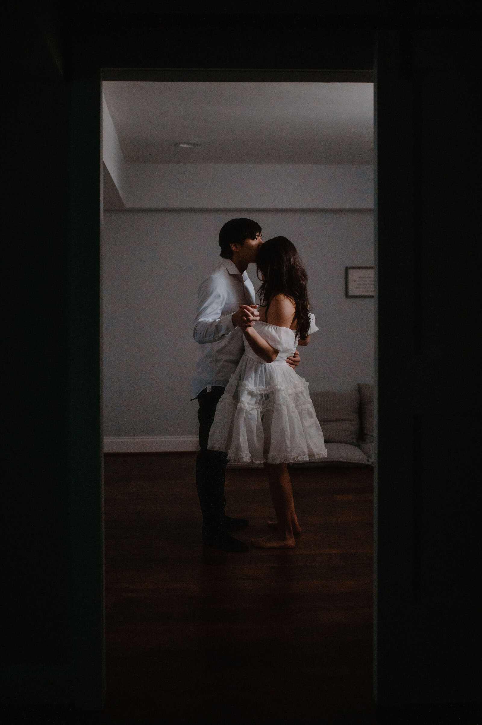 couple dancing barefoot in their home, single window lighting them