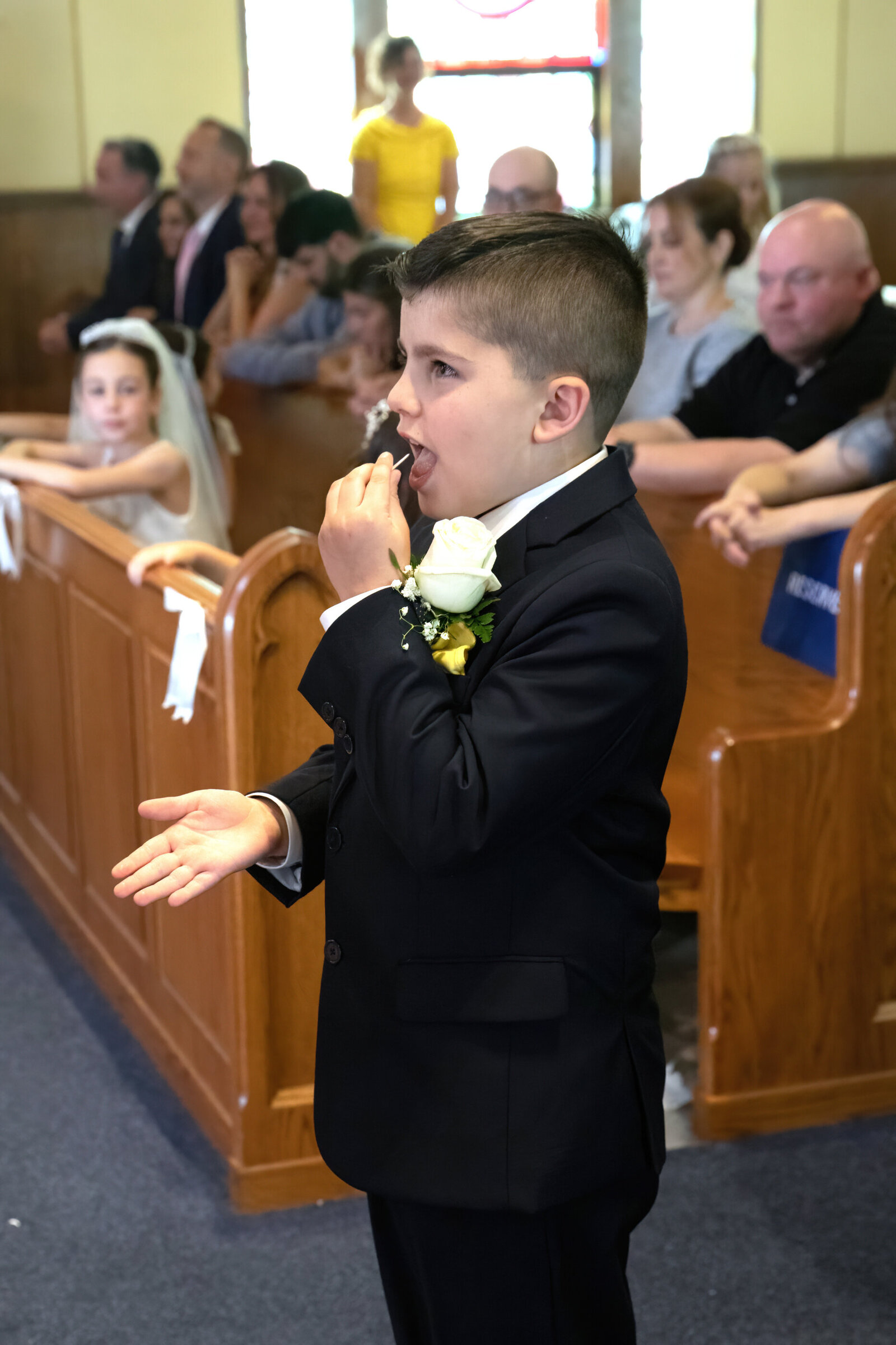 A young boy in a black suit receives a communion wafer New York First Communion photographer Milestone Images