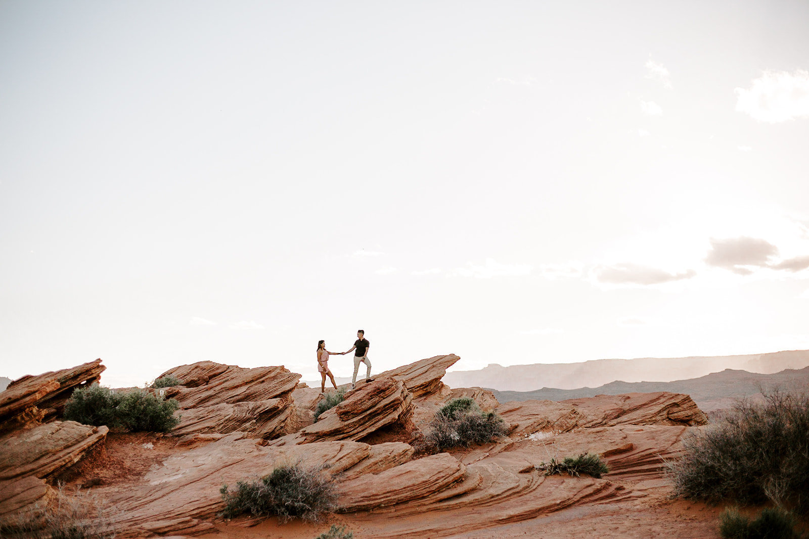 Couple holding hands walking together on a large rock during their Arizona engagement session