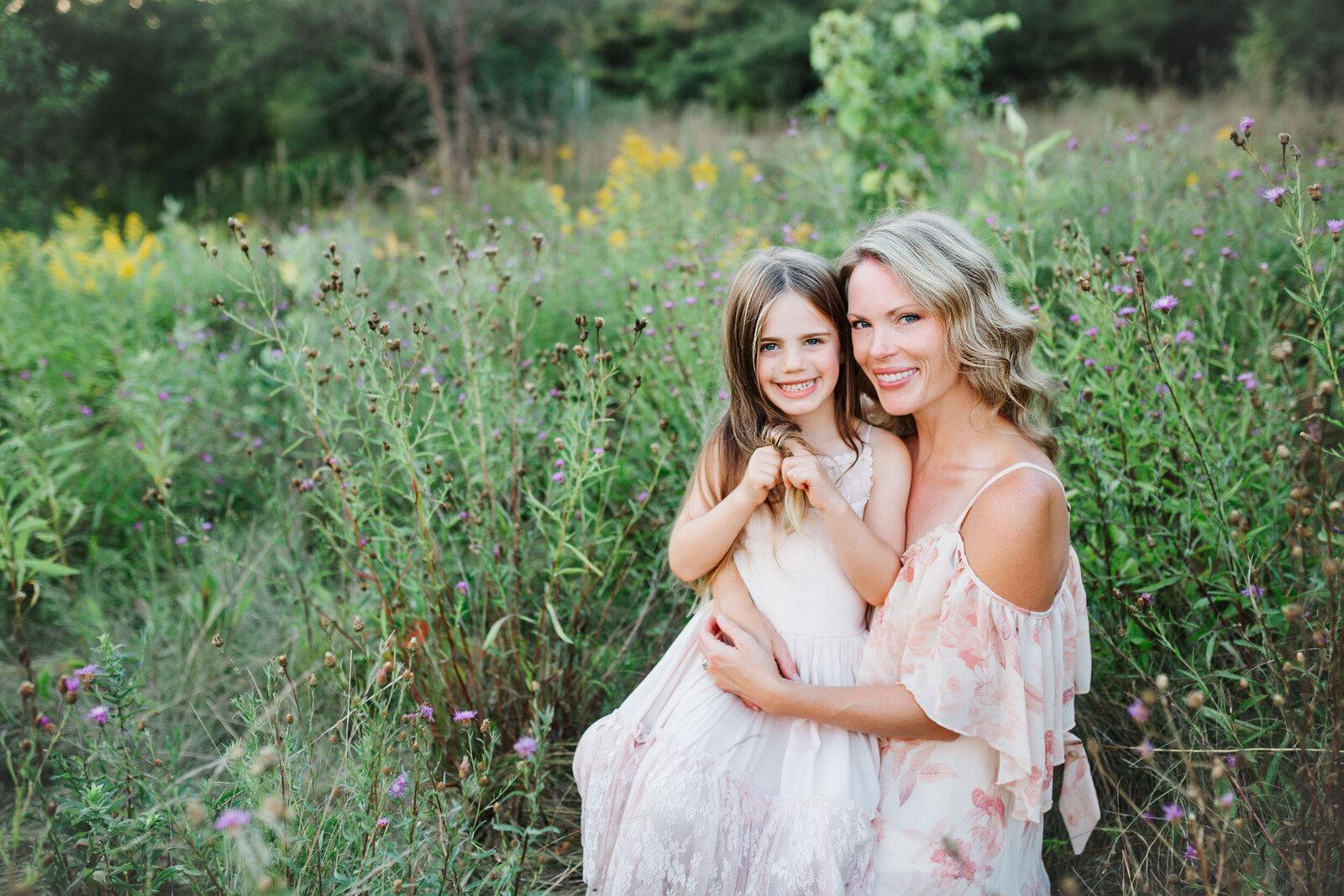 Mother and daughter snuggle in the tall grassy field