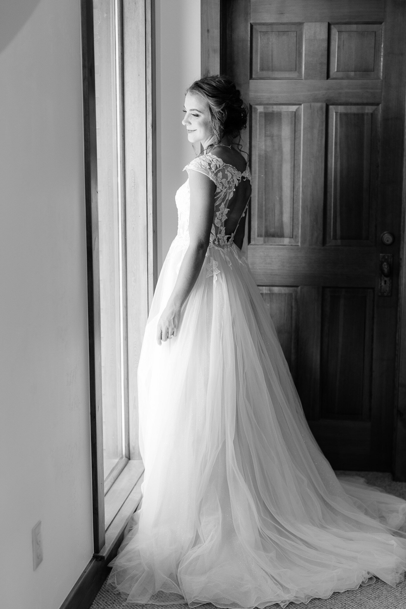 Black and white image of bride looking out window
