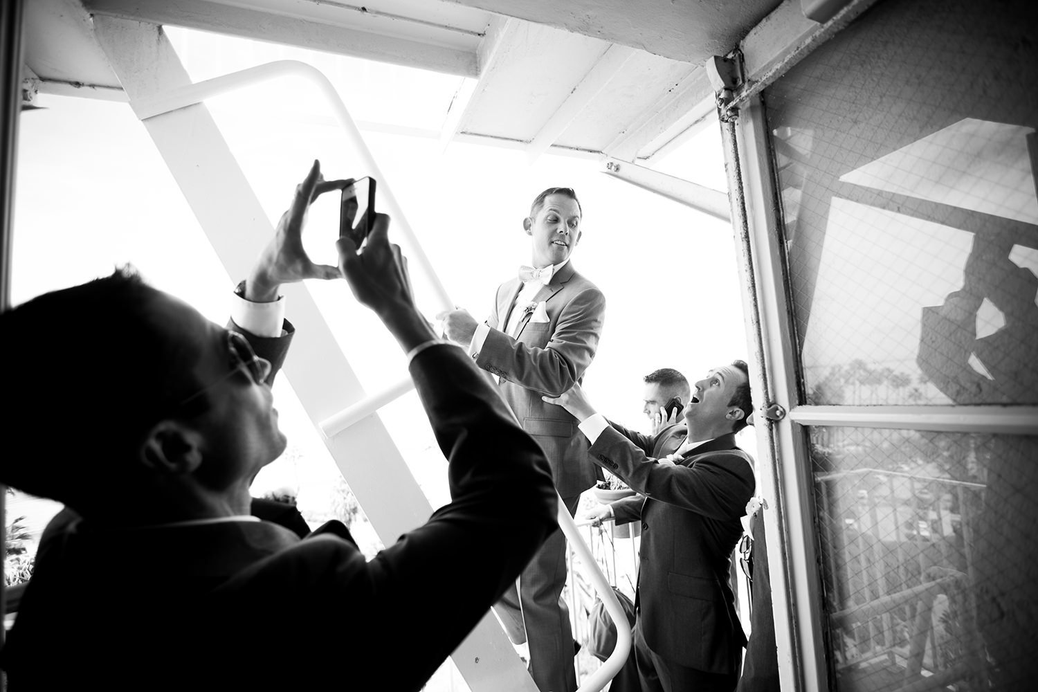 Photojournalistic moment captured of the groom and his groomsmen on the fire escape