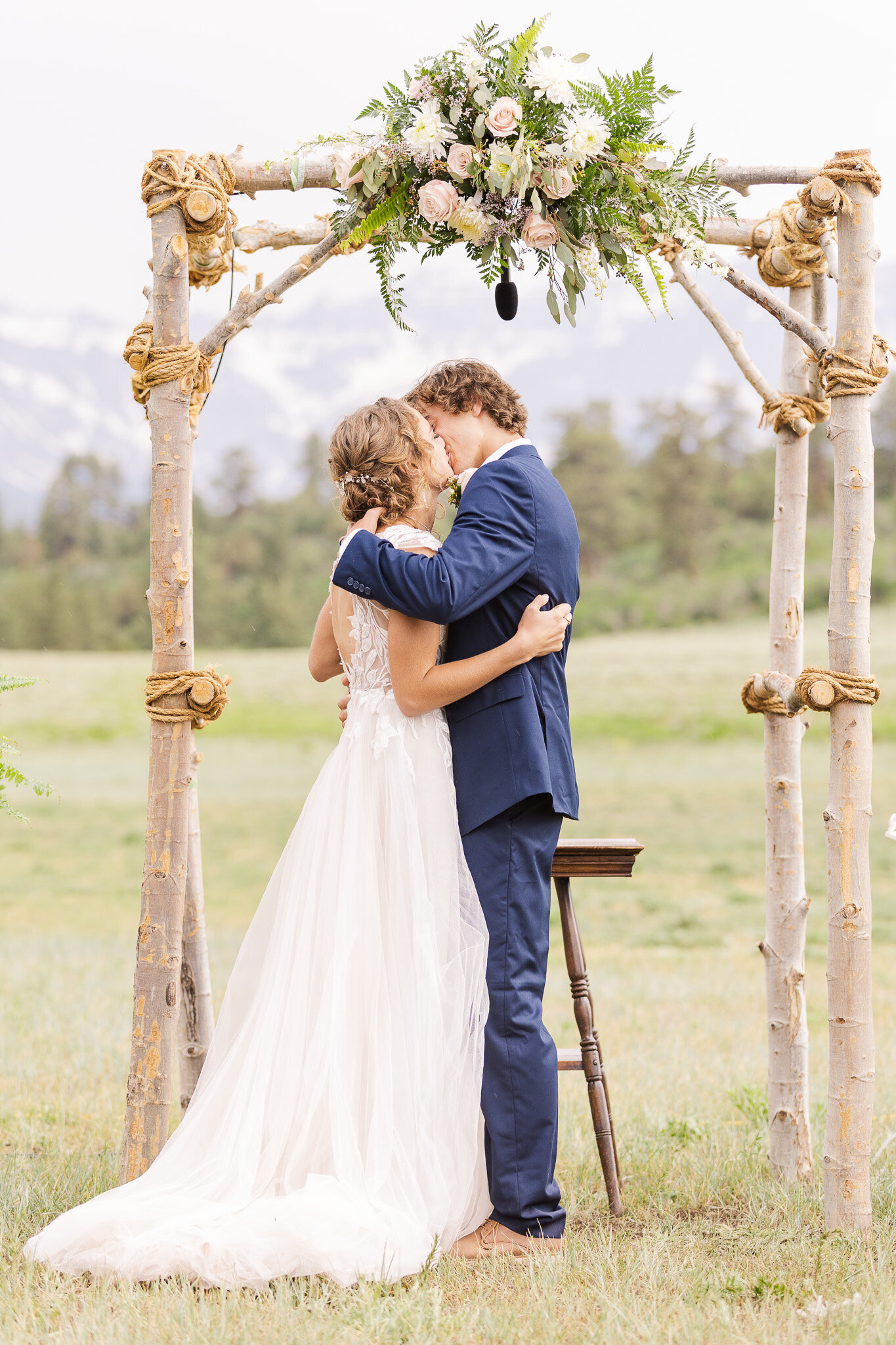 Bride and groom share a first kiss at top of the pines