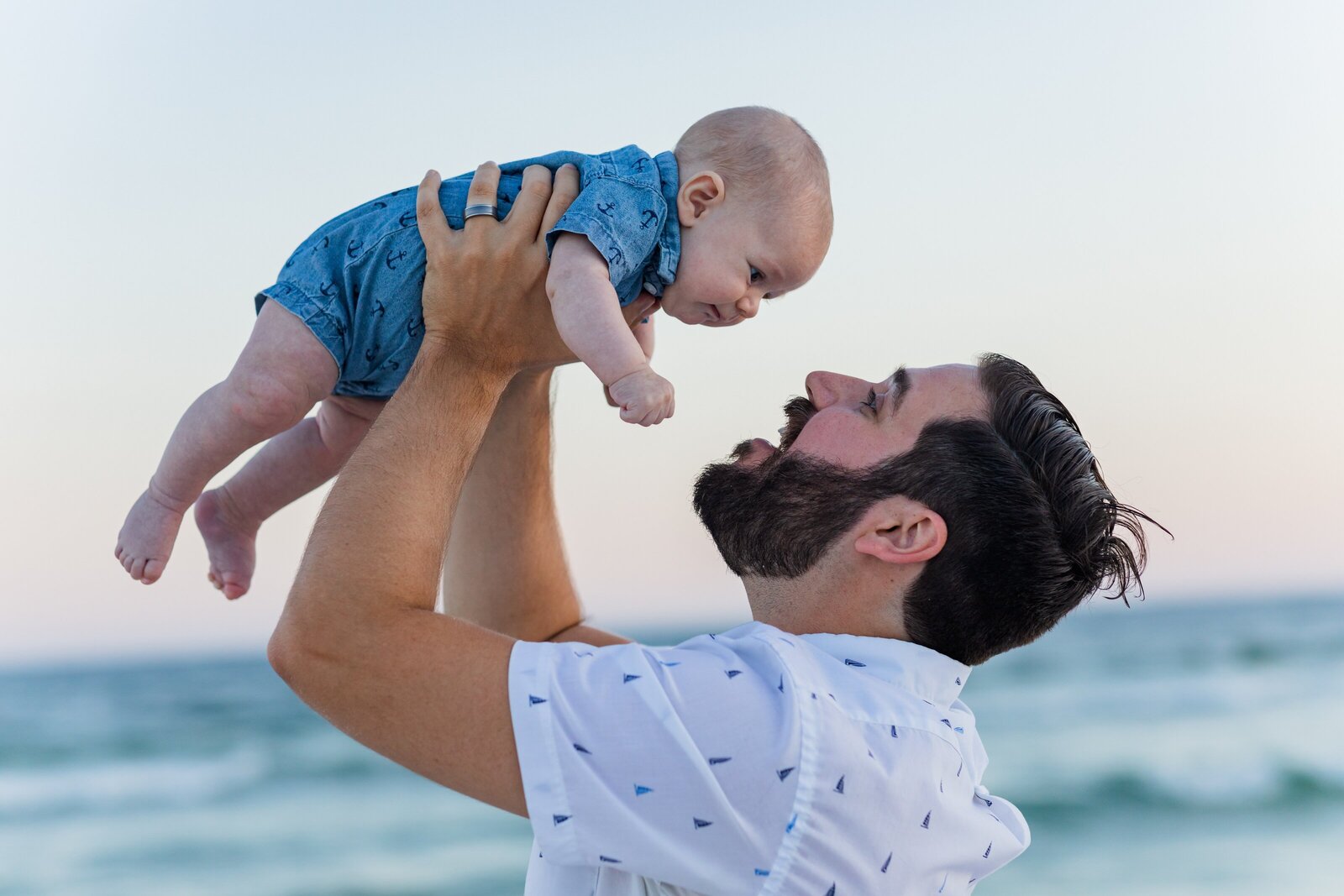 Father holding newborn son above his head on Pensacola Beach