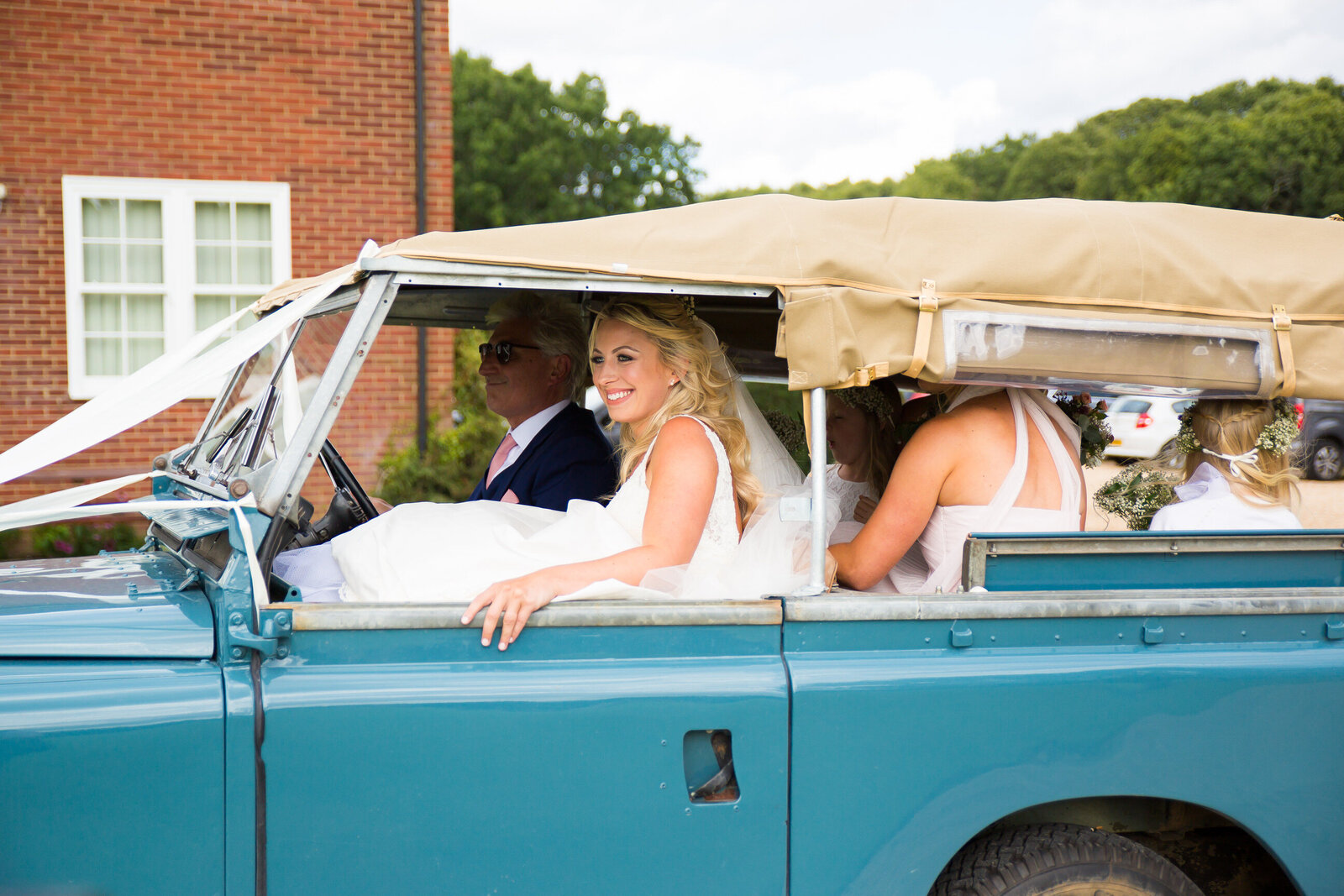 Wedding photography of a bride in a car on her way to get married at Highfield School Capel in Surrey. Photography by Lynsey Grace Photography.