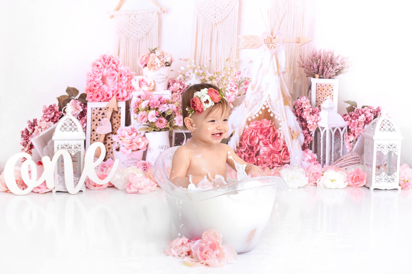girl splashes at her milk bath photoshoot for her first birthday in houston