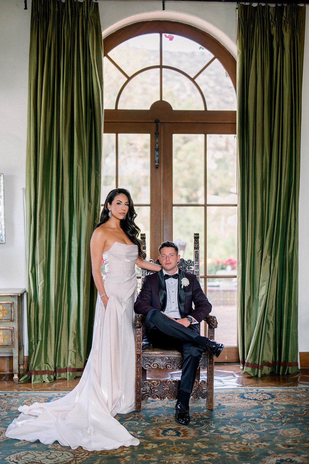 Bride and groom framed by luxurious velvet curtains in an elegant editorial portrait at Hummingbird Nest Ranch.