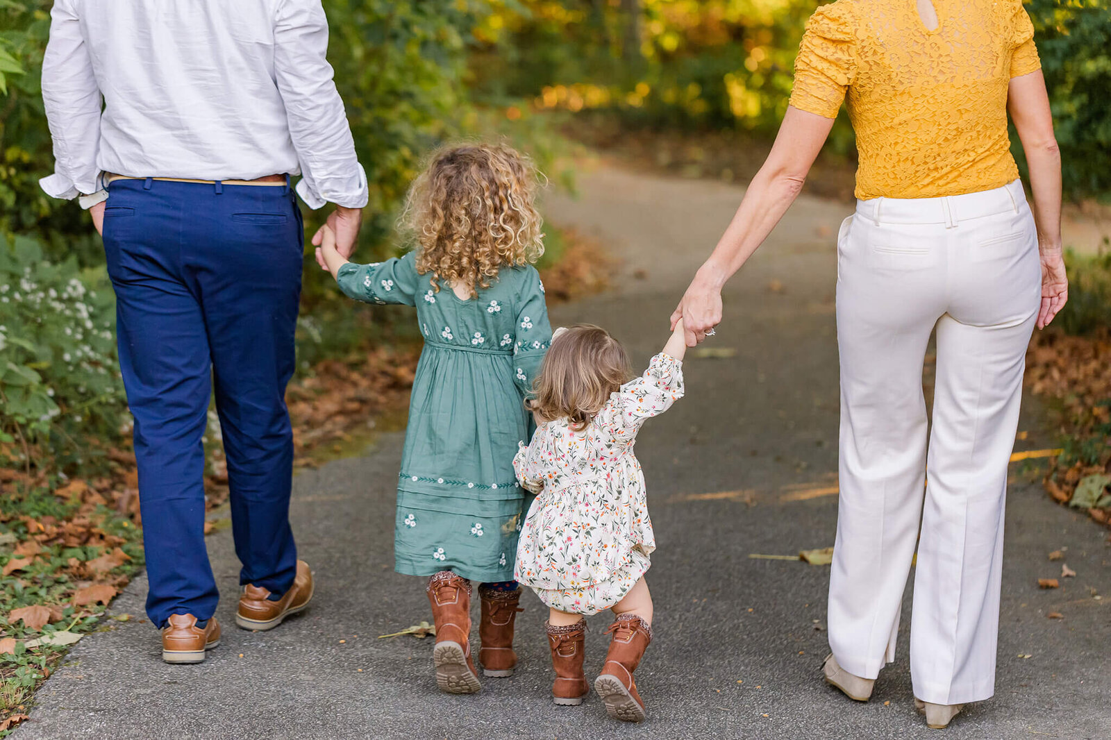 A mom and dad walking down a path with their two daughters during a session with Northern Virginia family photographer, Melissa Driggers.
