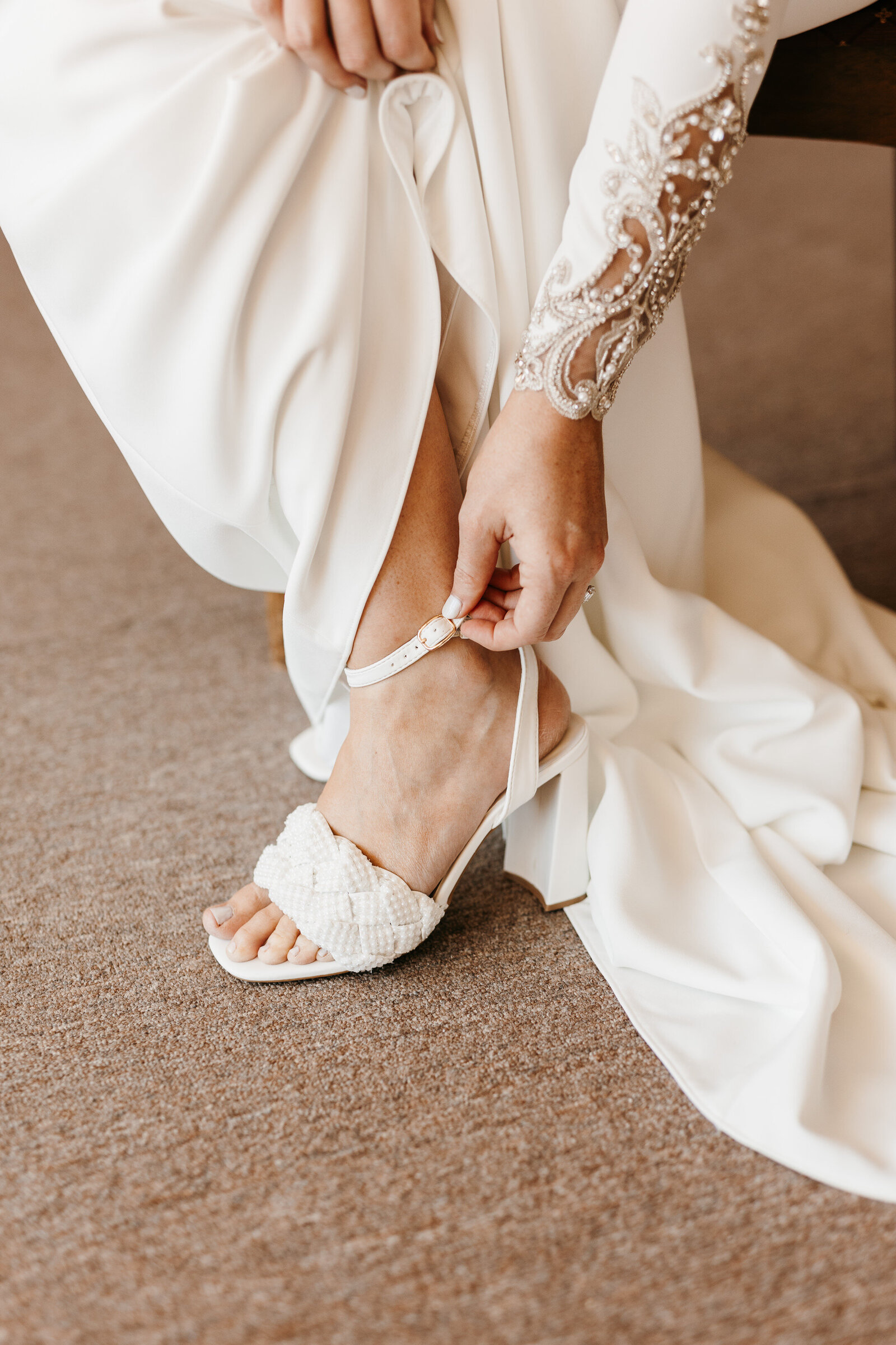 Bride fastening her floral bridal heels - Alex Bo Photo