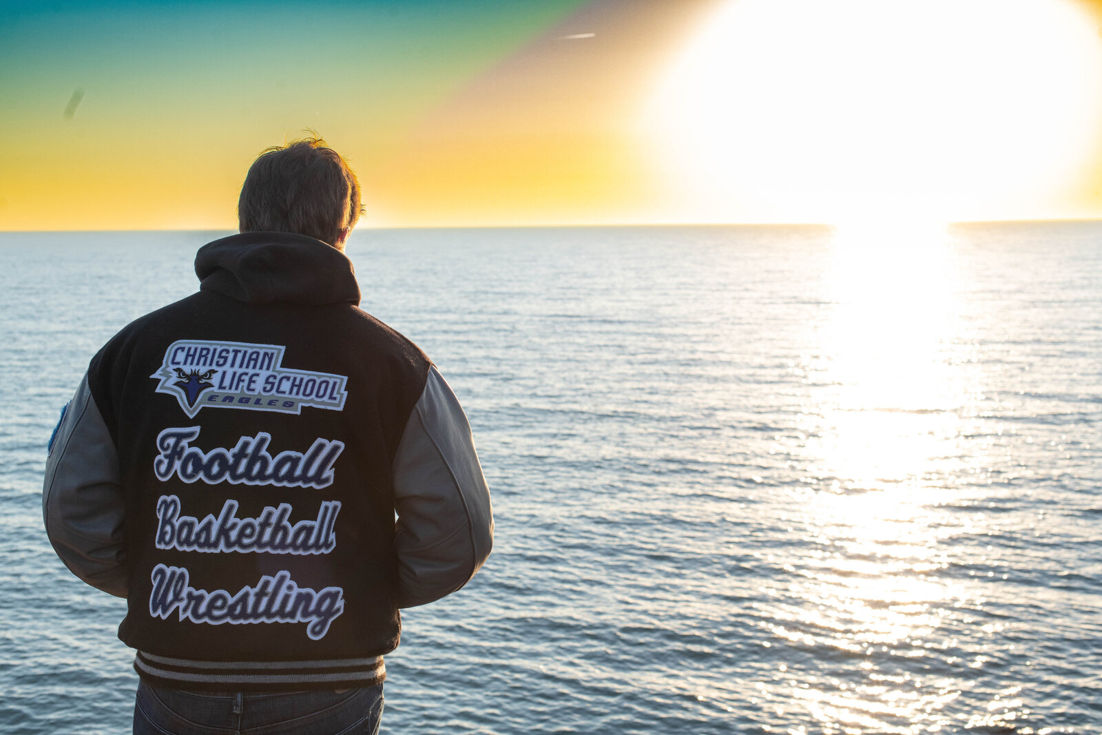 senior boy by lake in lettermans jacket