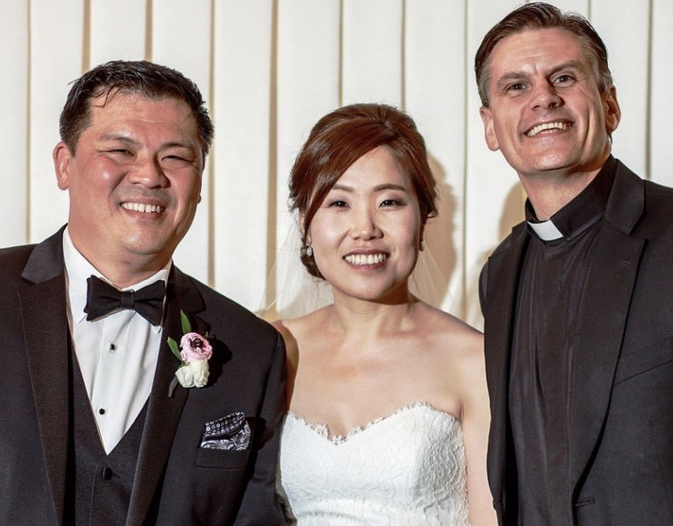 Bride, groom, and wedding officiant smile for portrait after wedding ceremony