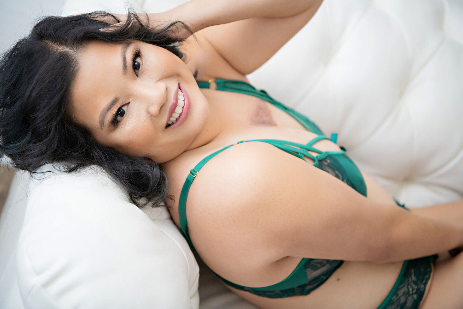 Asian woman in green lingerie set smiling in boudoir portrait