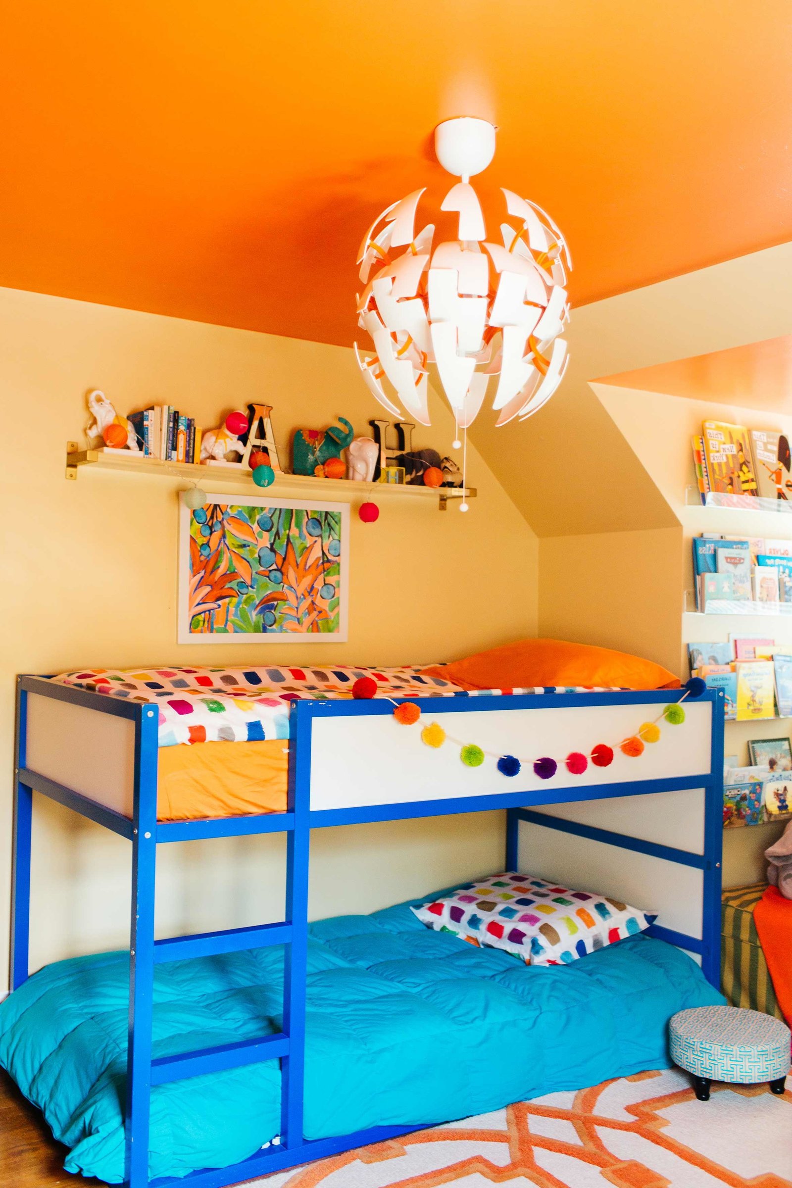 A boys bedroom with blue bunk beds and pom pom garland.