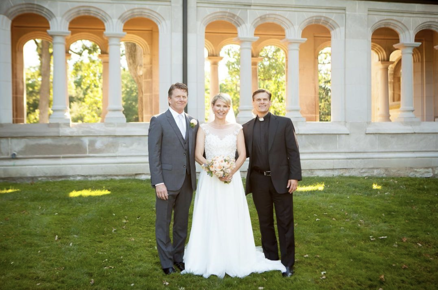 Bride, groom, and wedding officiant pose for portrait after wedding ceremony