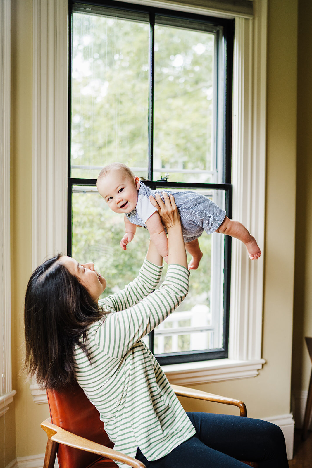 mom lifts baby in air during boston home family photos