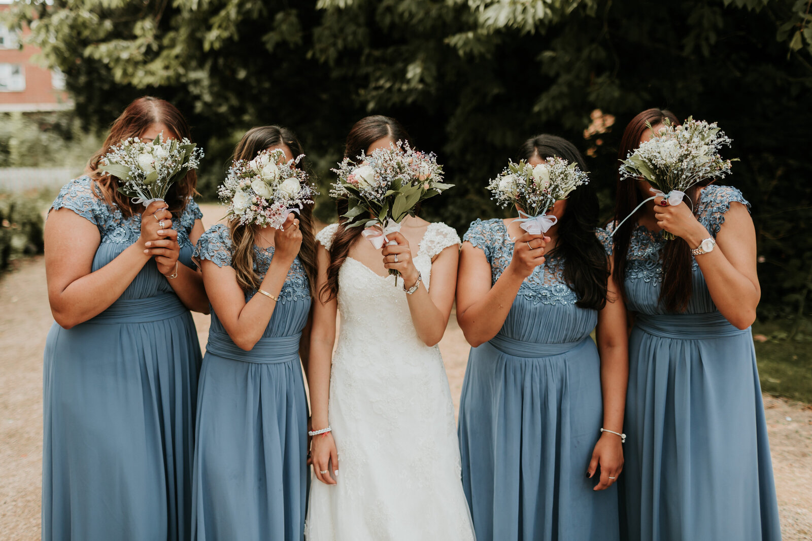 Bridesmaids with flowers up covering faces