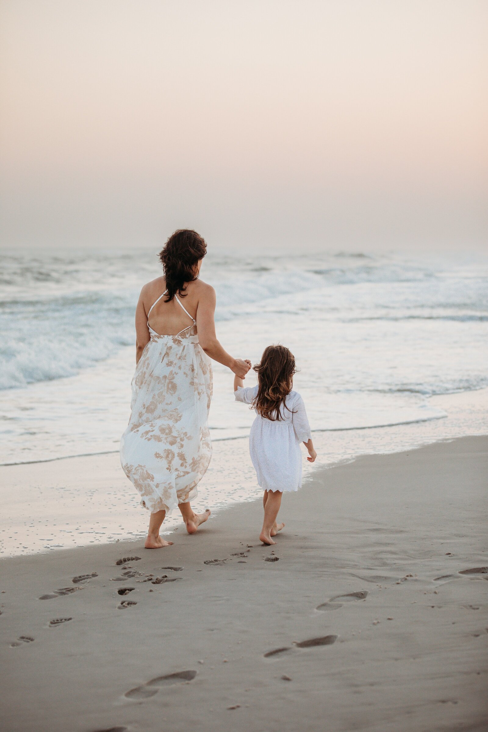 Pensacola Beach Family Photography Session. Mother and daughter holding hands walking down the beach.